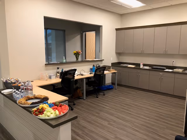 Empty staff break room with counters, cabinets, and fruit platters.