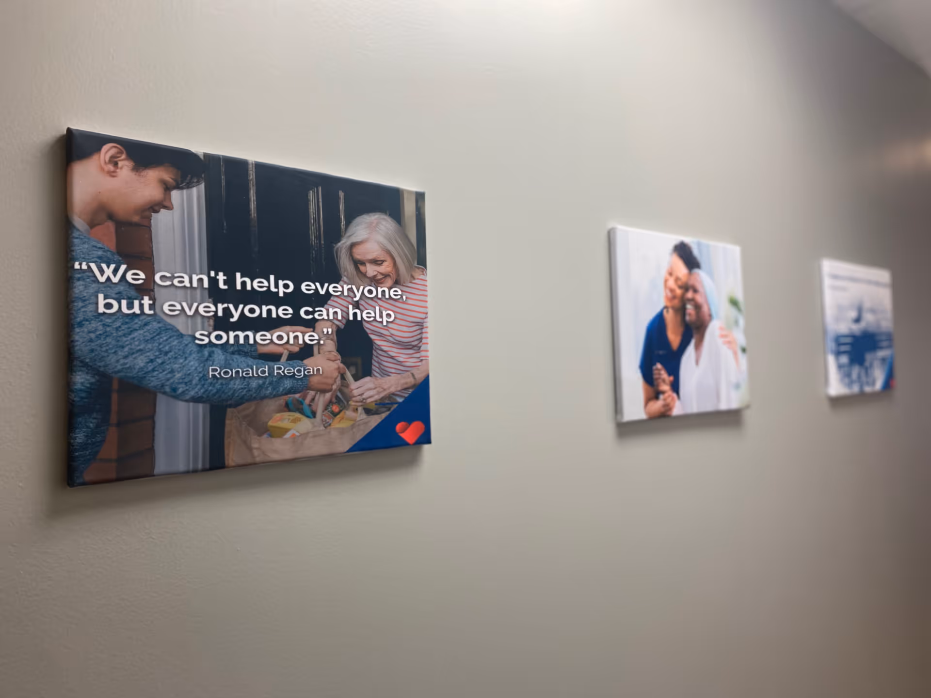 Gray hallway wall displays three framed posters with inspirational quotes and photos.