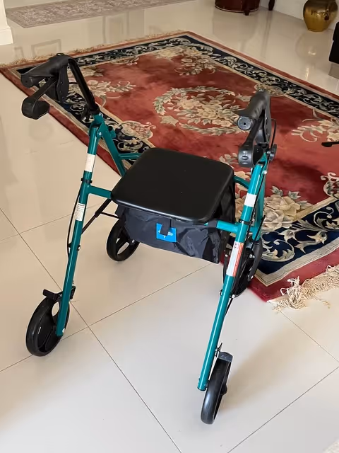 Teal foldable walker with a black seat sits on a tiled interior floor beside a rug.