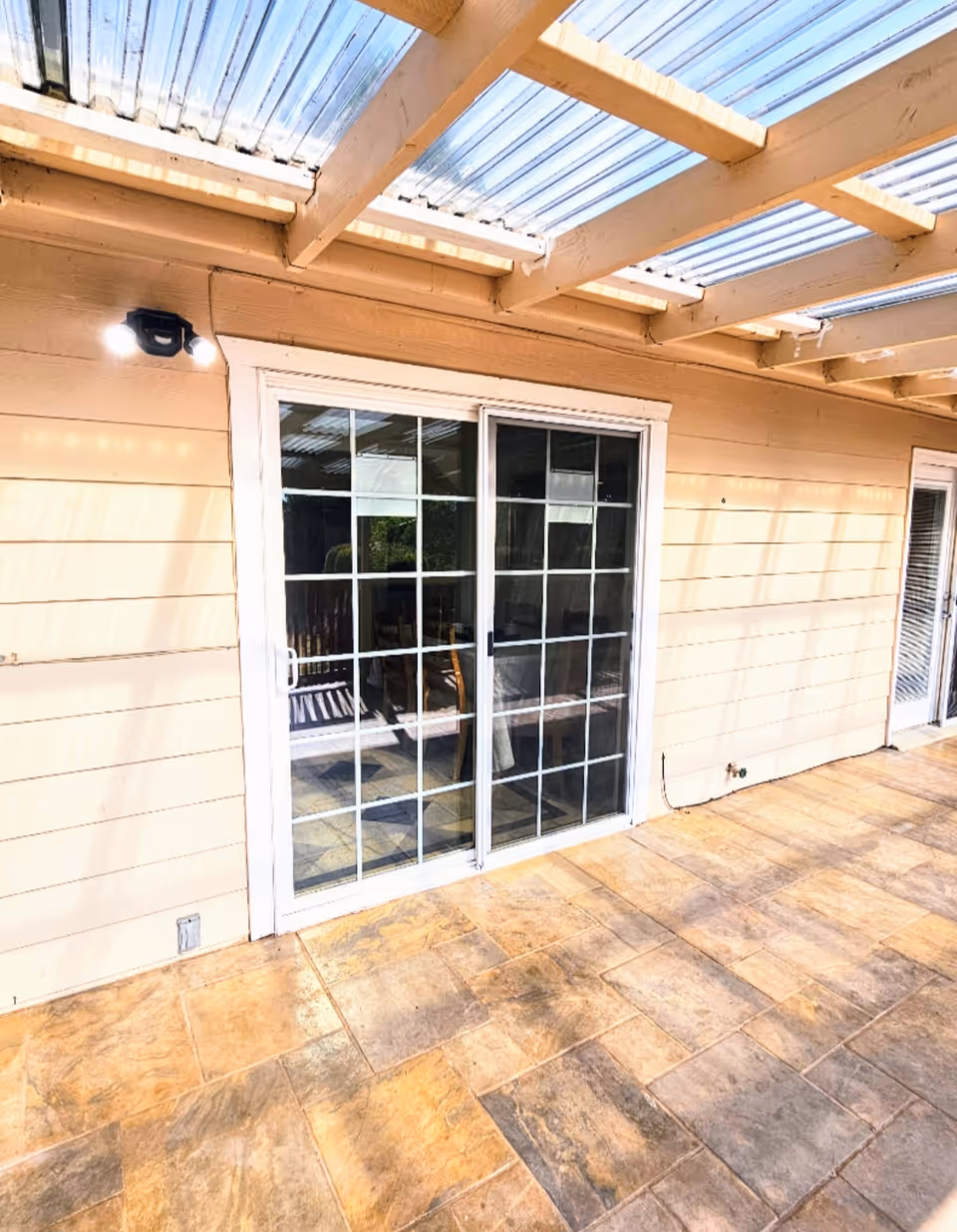 Beige exterior with sliding glass doors leading to a covered outdoor patio area.