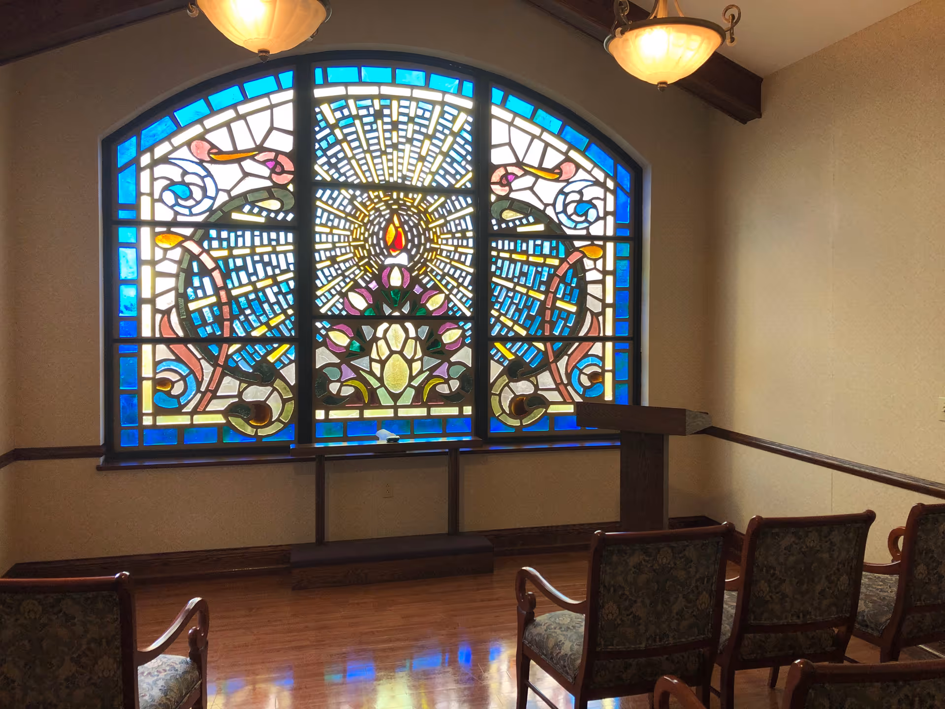 Interior room with a large stained glass window, podium, and row seating