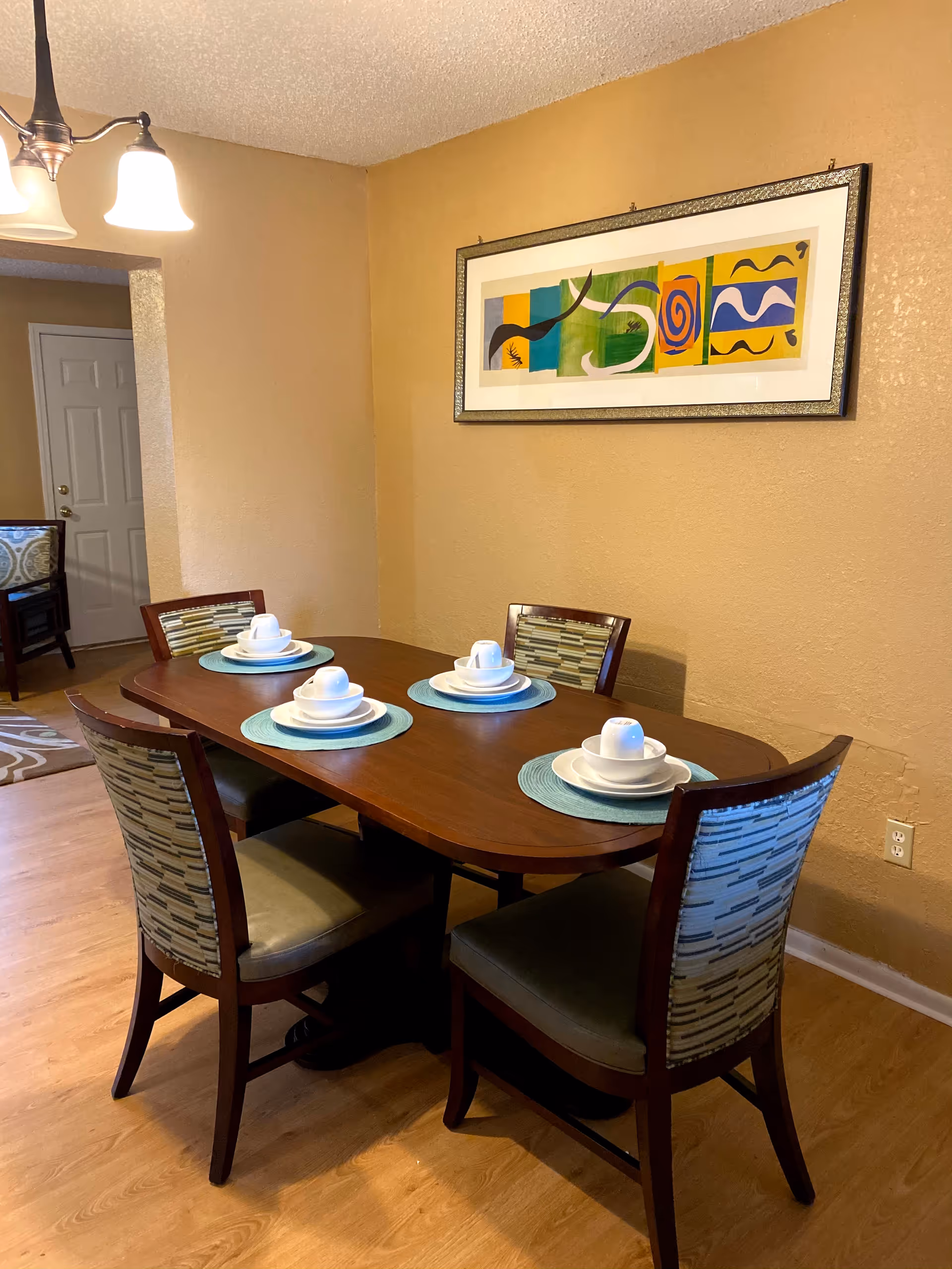 Dining room featuring a wooden table set for six with colorful wall art.