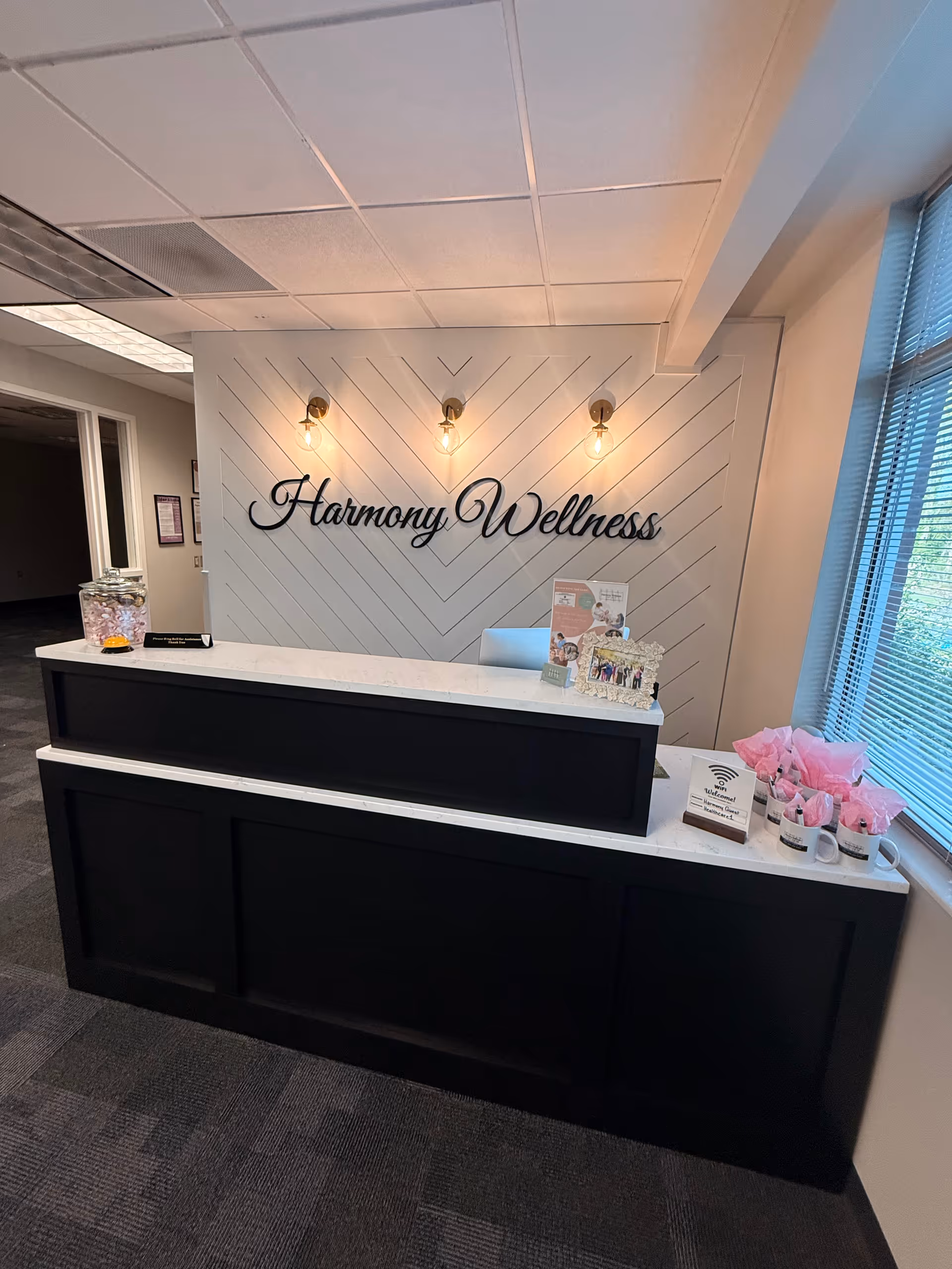Reception desk in Harmony Wellness lobby with wall signage and warm lighting