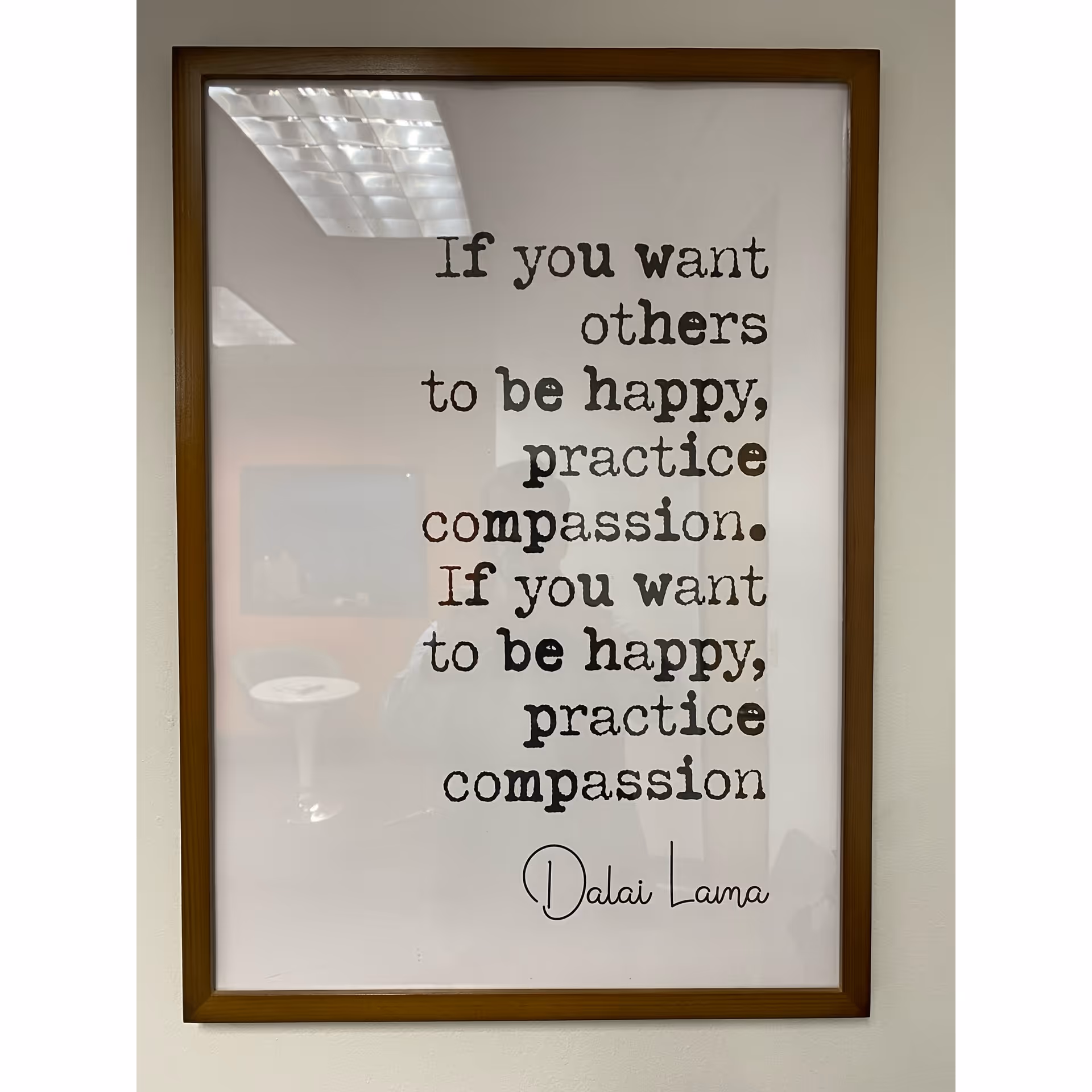Framed wall art with Dalai Lama quote on a beige interior wall.
