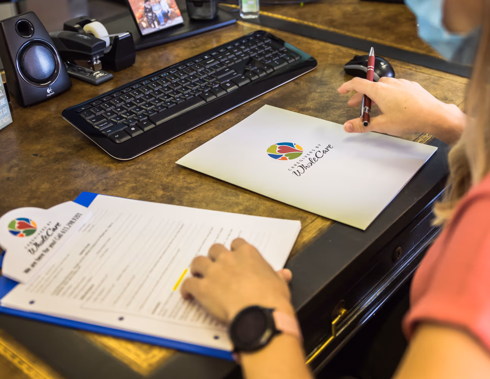 Office desk with documents, keyboard, and a pen next to a WholeCare envelope.
