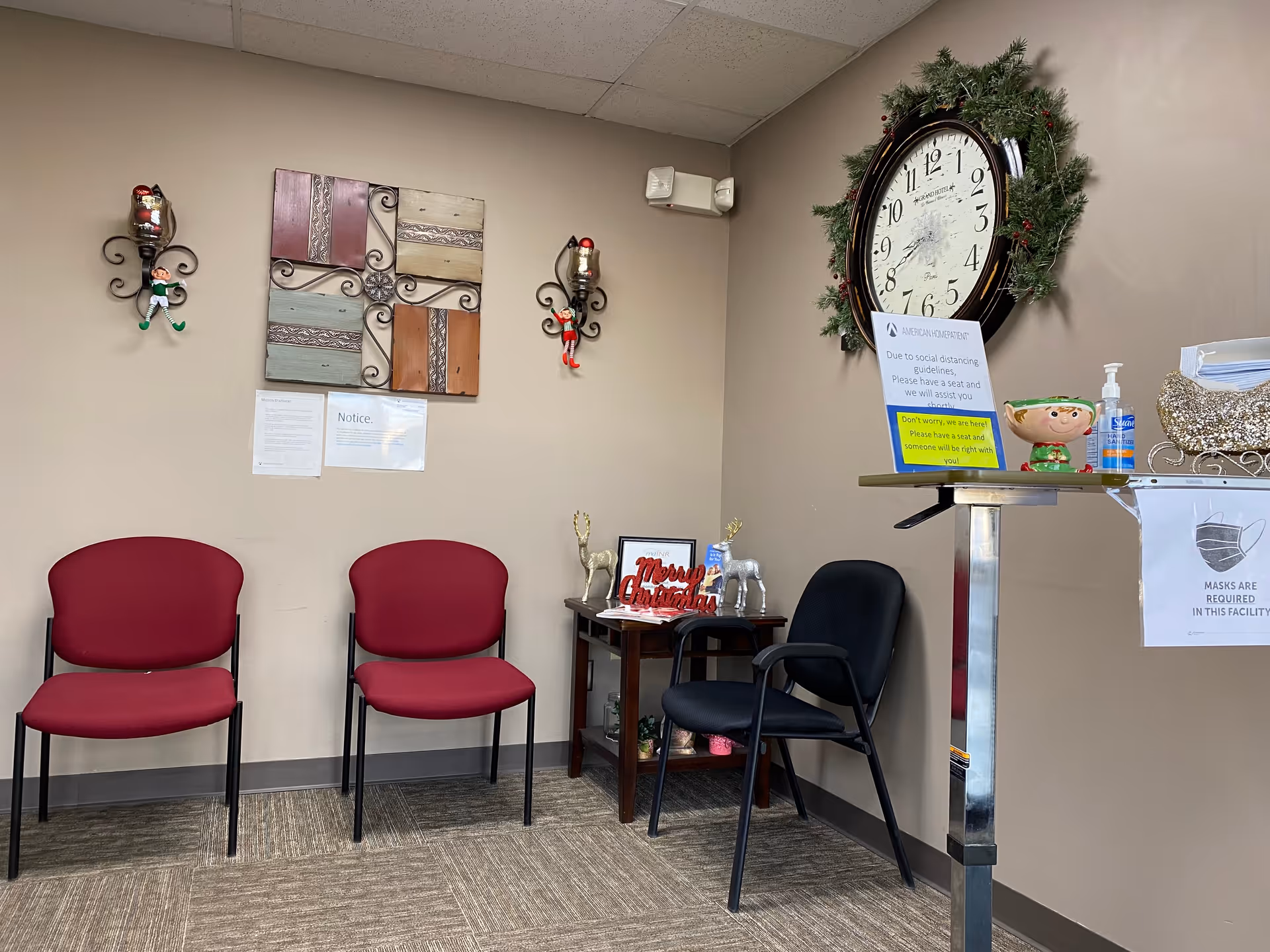 A small waiting area with red chairs, wall art, a large clock, and a reception counter.