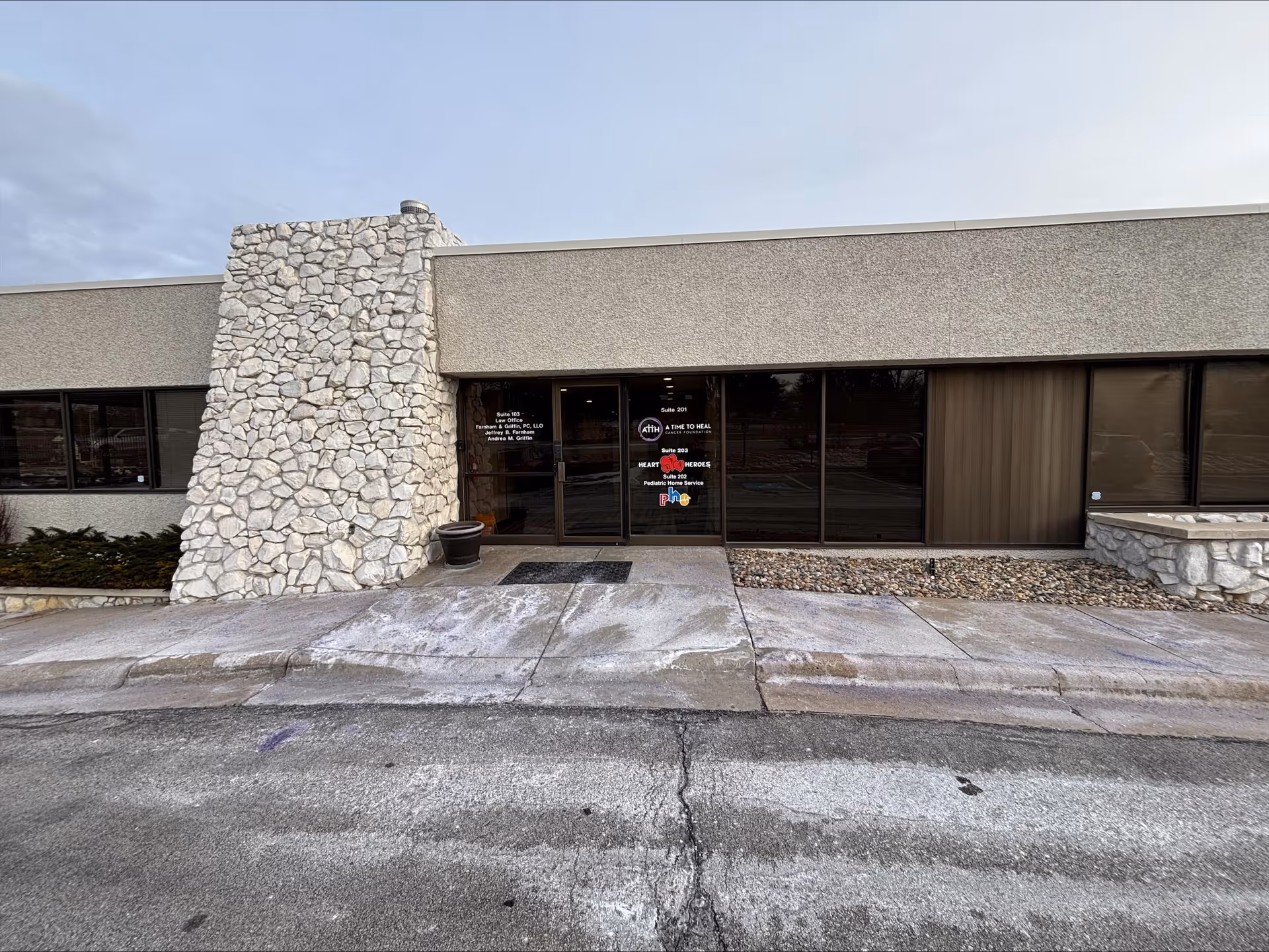 Exterior view of a single-story facility with stone pillar and glass entrance doors.
