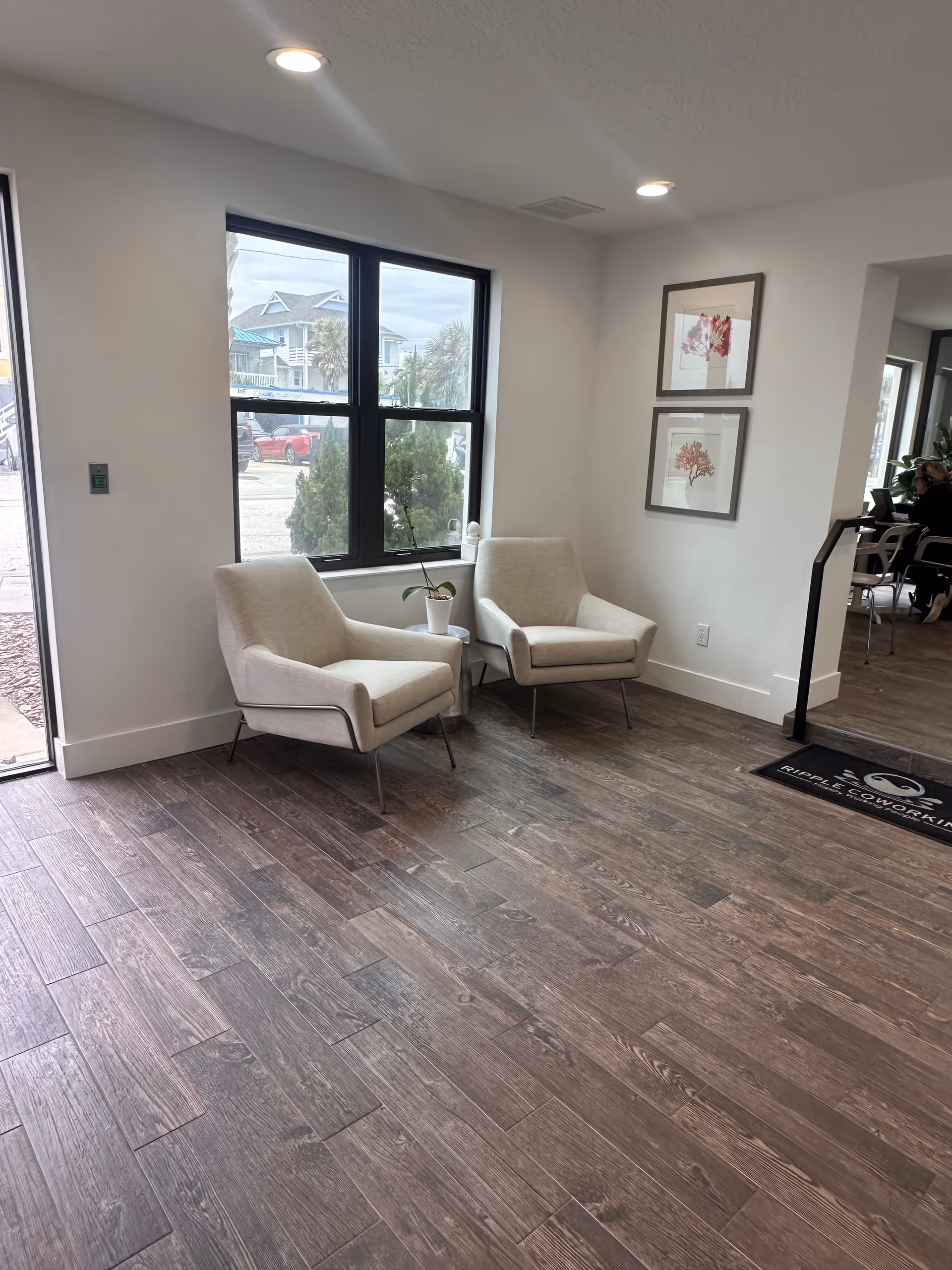 Two beige lounge chairs by a large window in a modern senior living lobby.