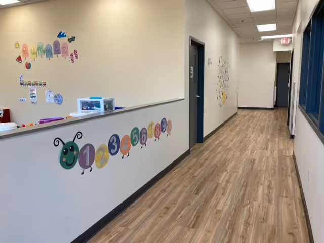 Bright hallway in a senior facility with a decorated wall and counter on the left.