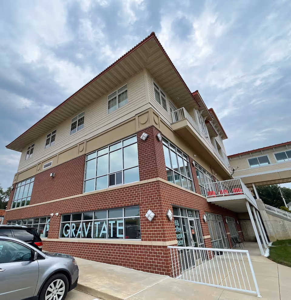 Two-story senior living facility exterior with brick lower facade and large glass windows.