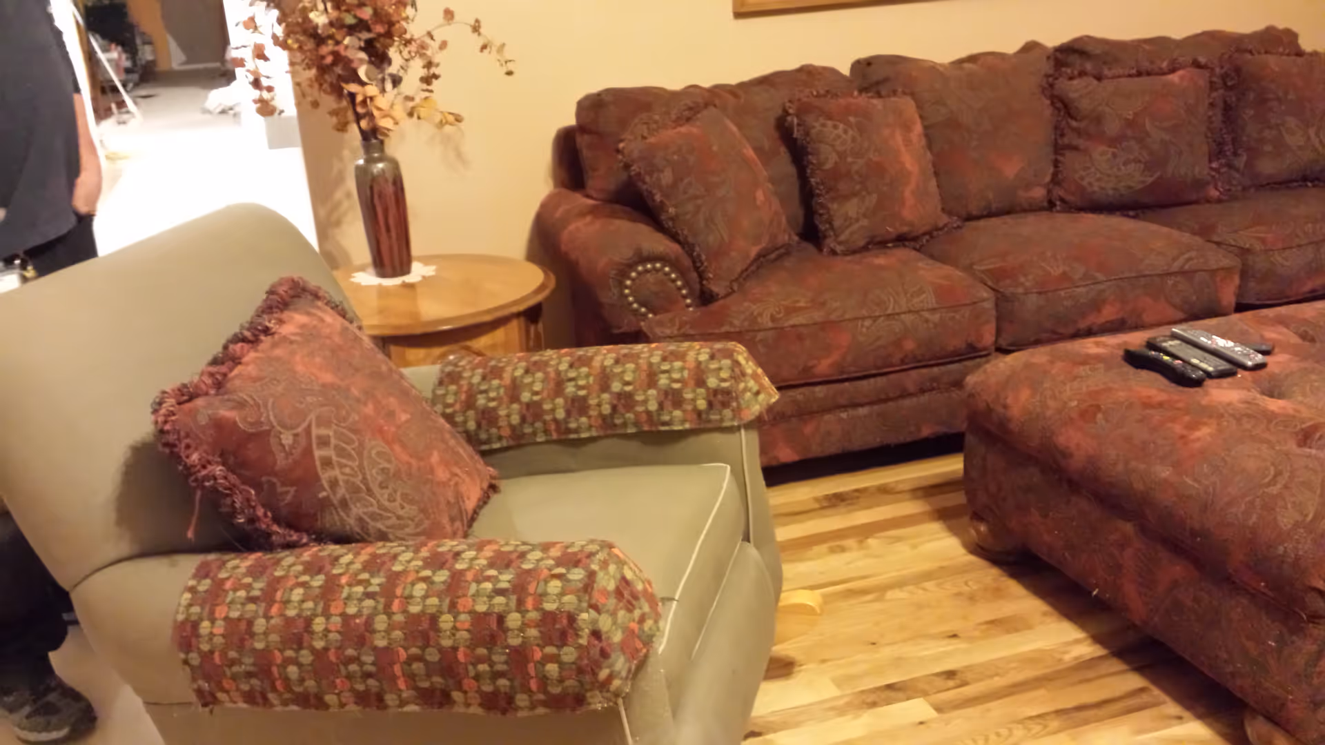 Cozy living room with burgundy patterned sofas, an armchair, wood flooring, and a decorative side table.