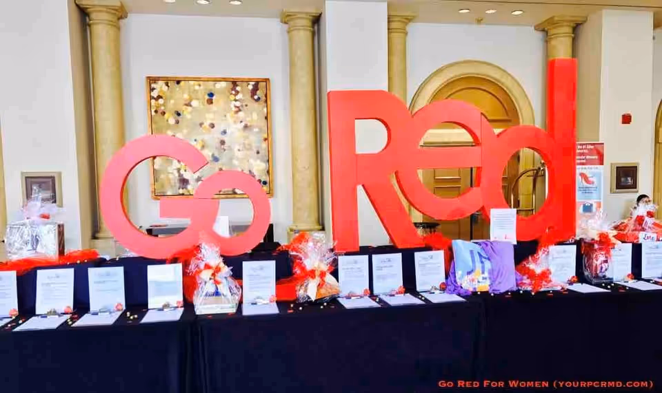 Large red Go Red display at a long conference table with awards and gift bags indoors.