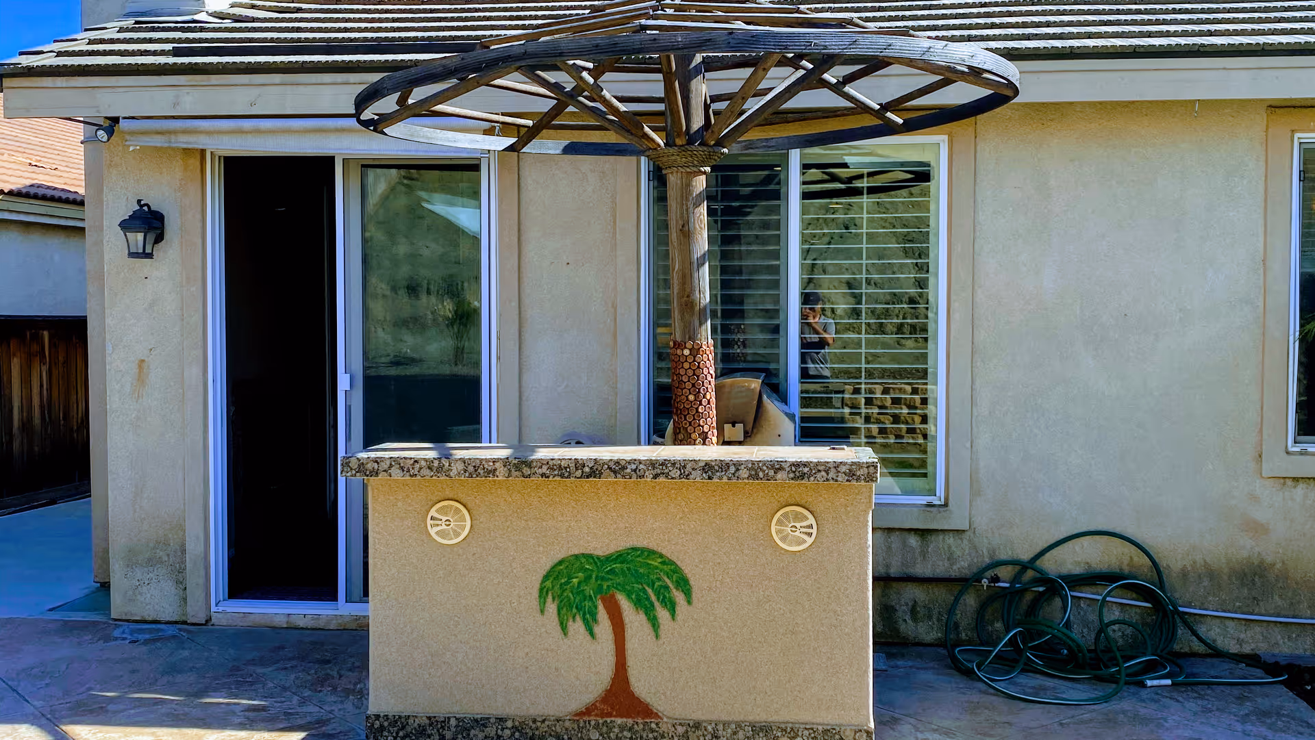 Outdoor patio with a counter featuring a palm tree mural beside sliding doors.