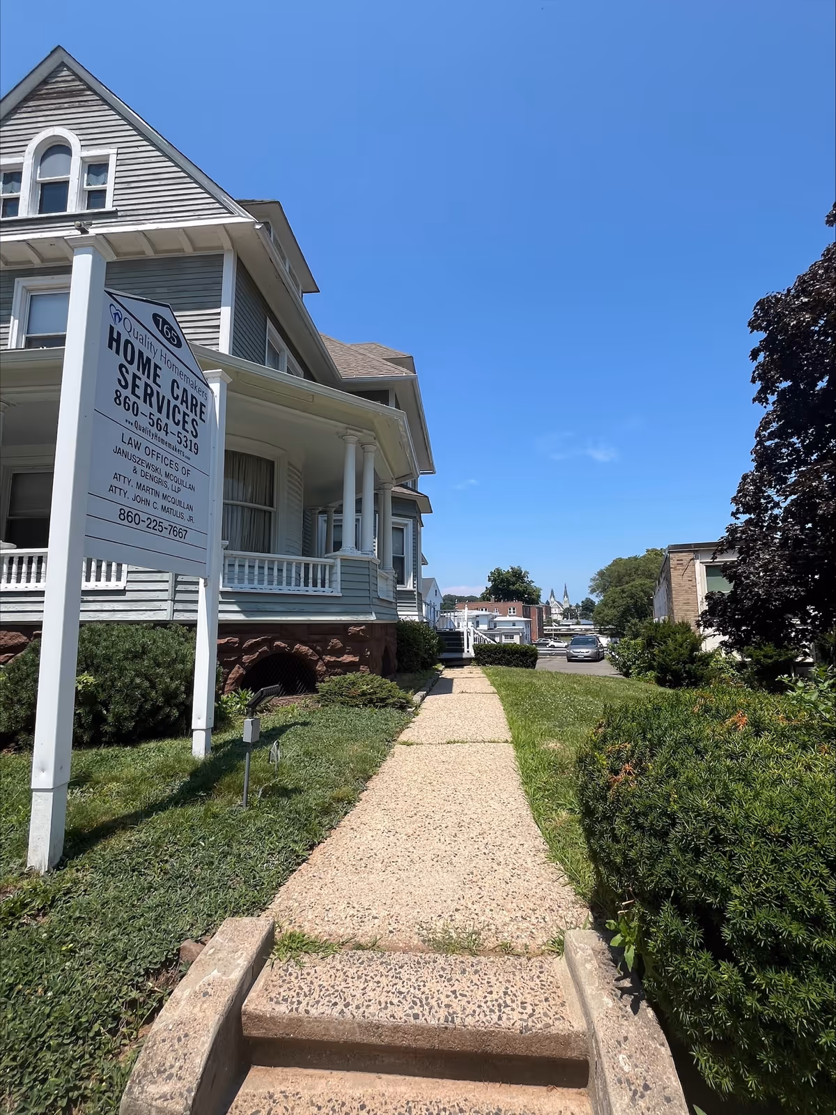 Exterior of a senior living facility with a large sign and pebble walkway.