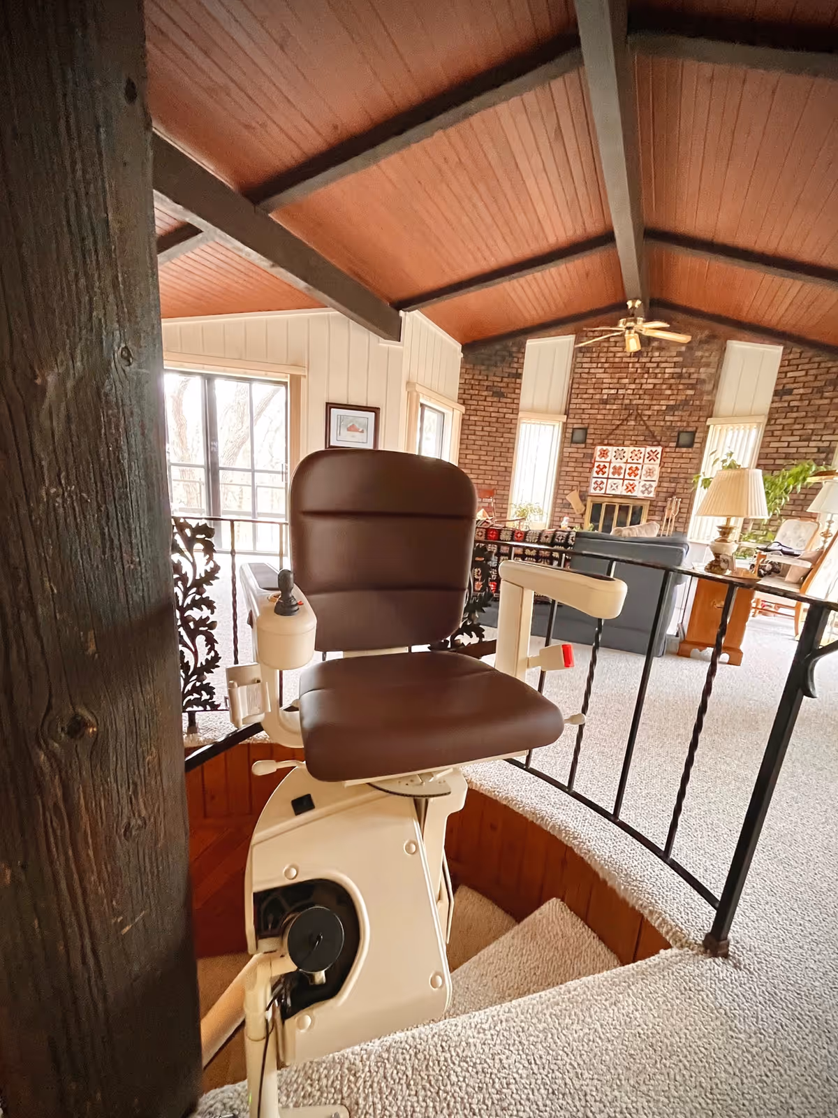 Curved staircase with a brown stair lift chair in a cozy living area.