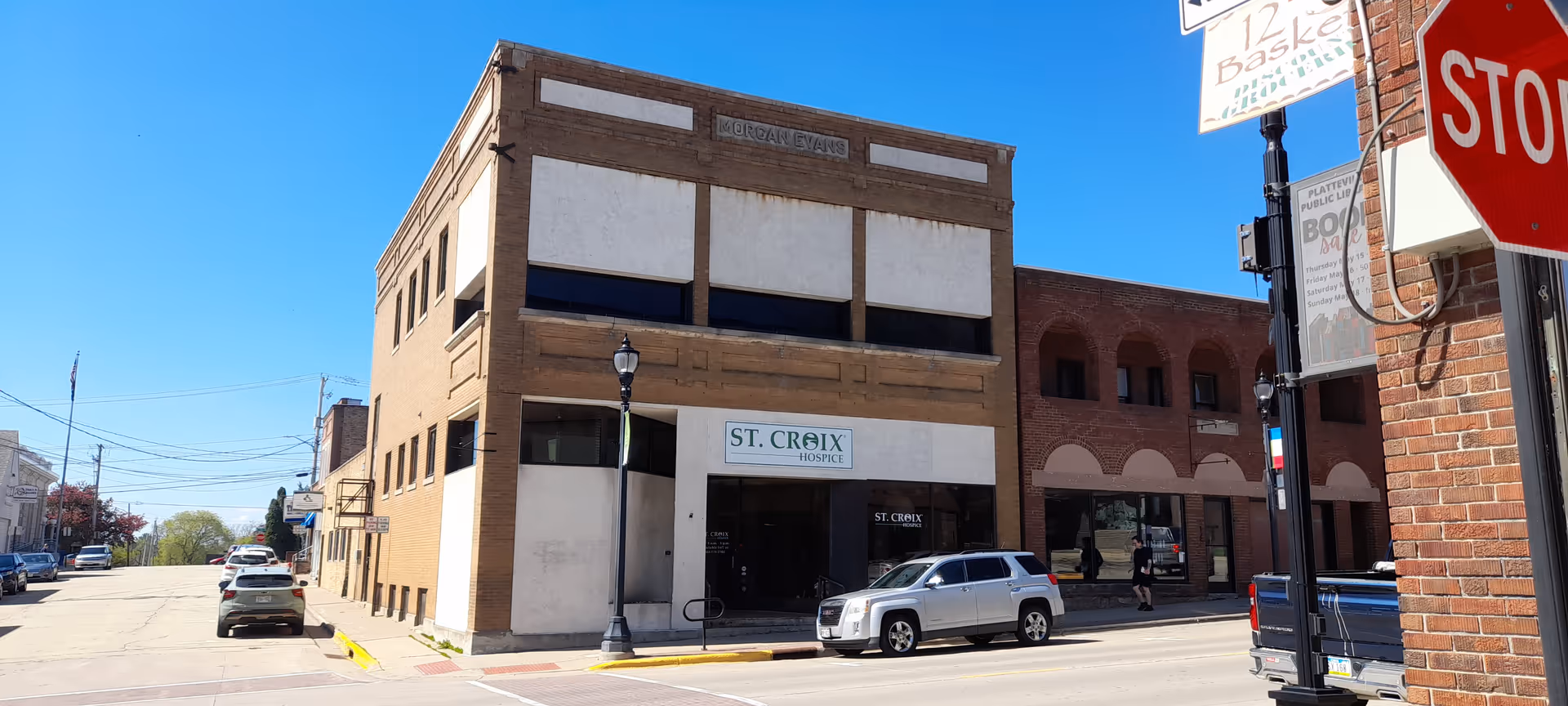 Sunlit street view of a brick building with a St. Croix Hospice sign.