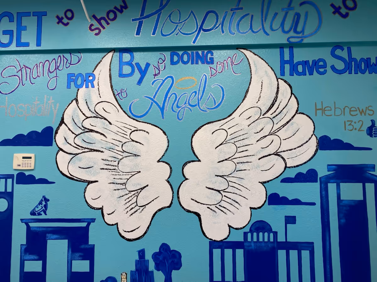 Blue interior wall mural with large angel wings and inspirational phrases.