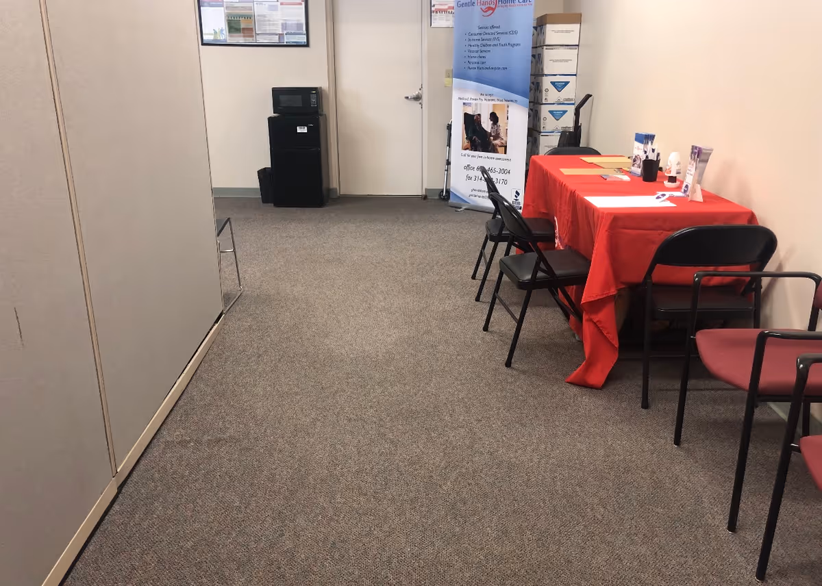 The empty office hallway has a red table, banner stand, and black chairs.