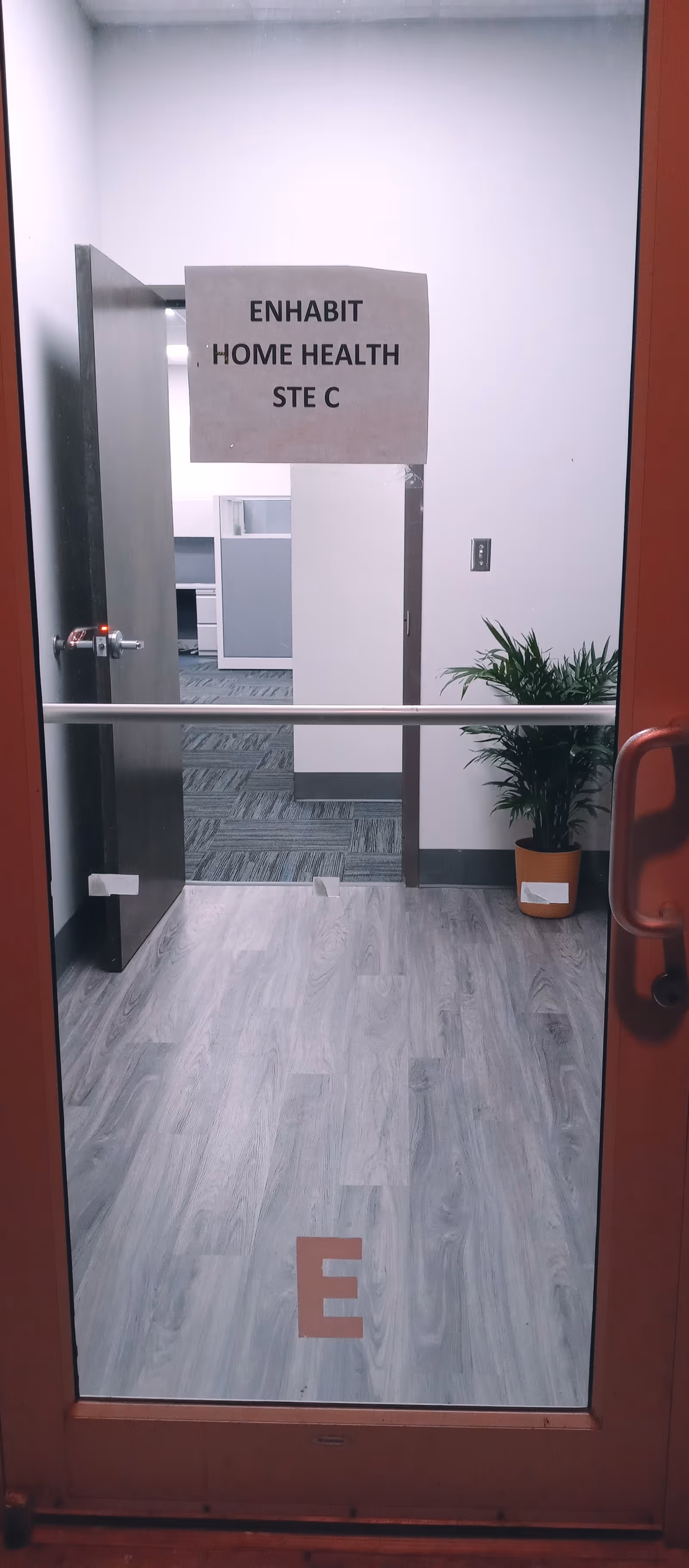 Interior hallway with Enhabit Home Health sign on wall and a potted plant.