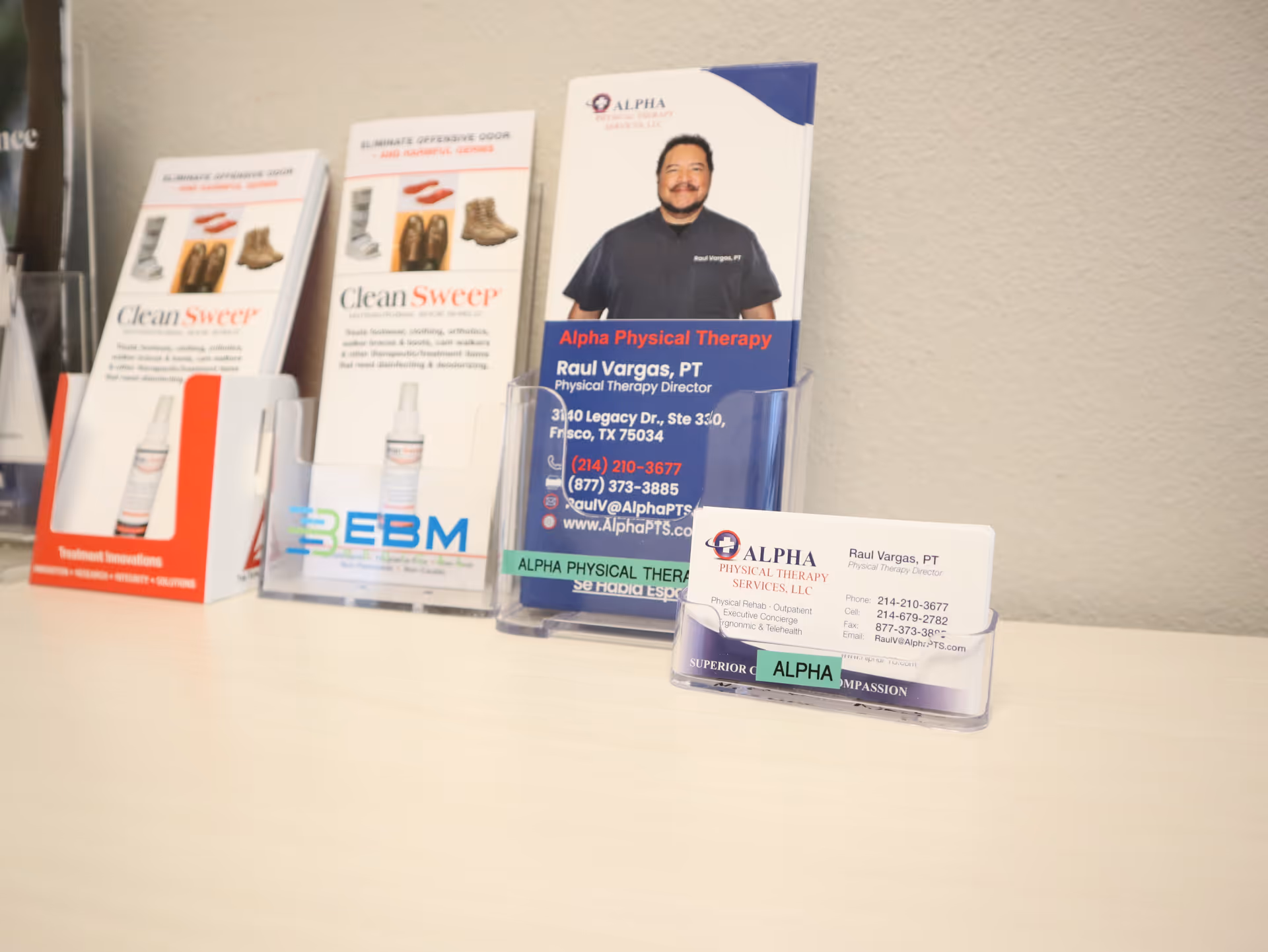Display of Alpha Physical Therapy brochures and business cards on a light tabletop.