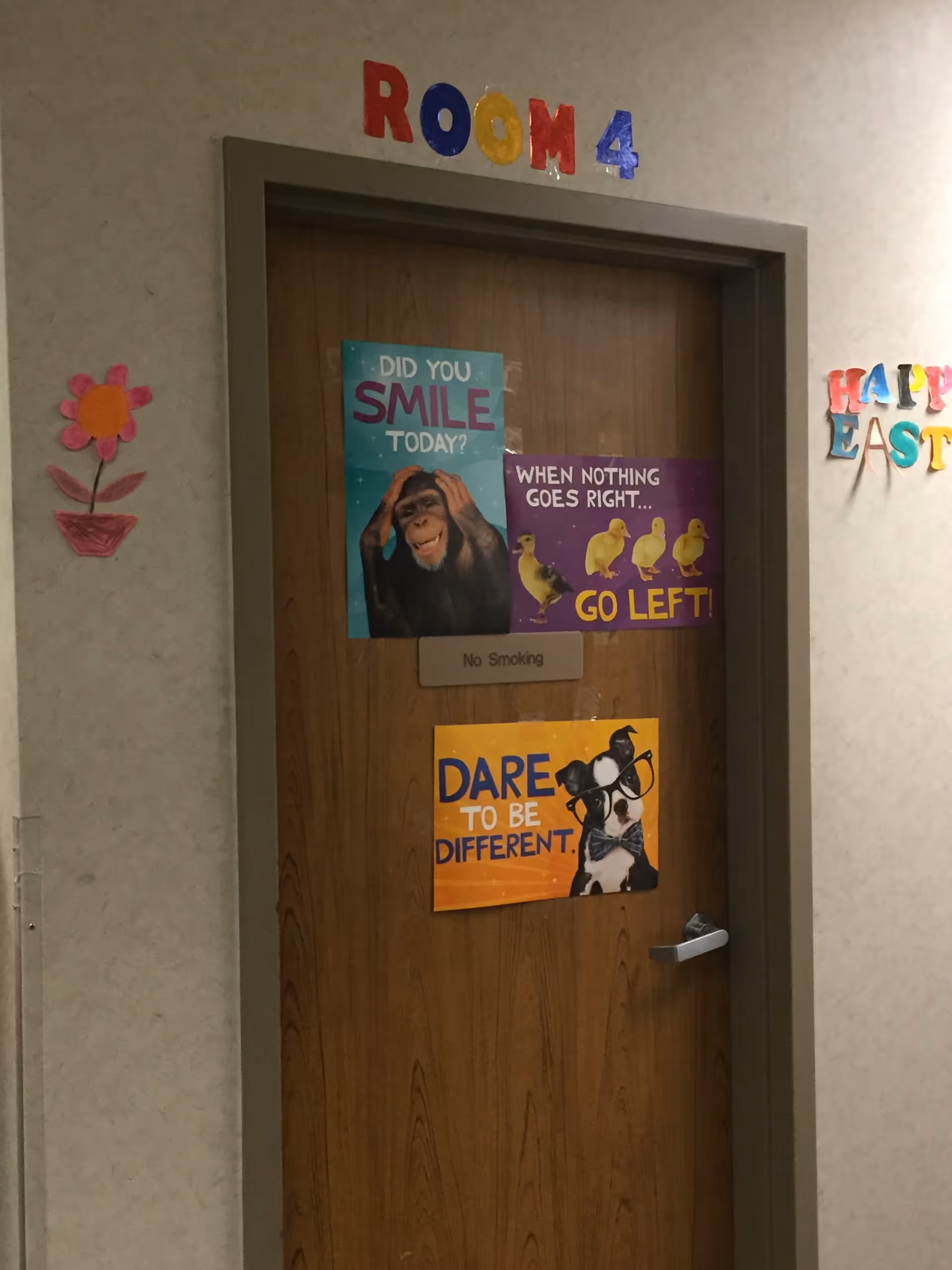 Wooden door labeled ROOM 4 with colorful posters and wall decorations in a hallway.