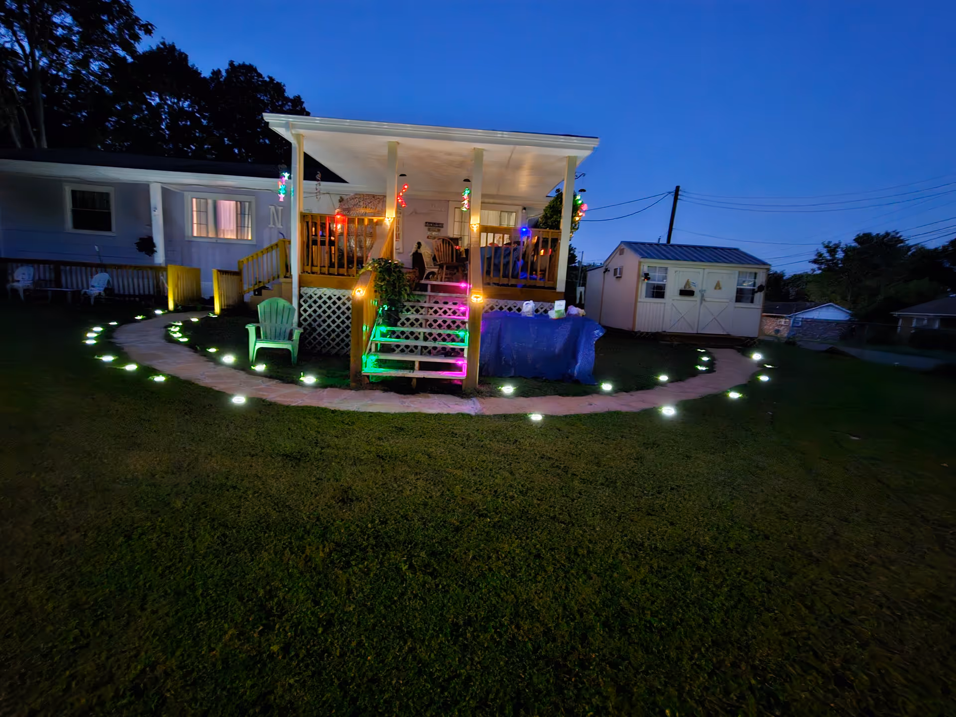Exterior view of a house with rainbow-lit porch and a circular illuminated walkway.