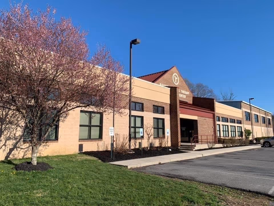 Exterior view of Rankin Home Health facility with pink blossoms, brick facade, and parking.