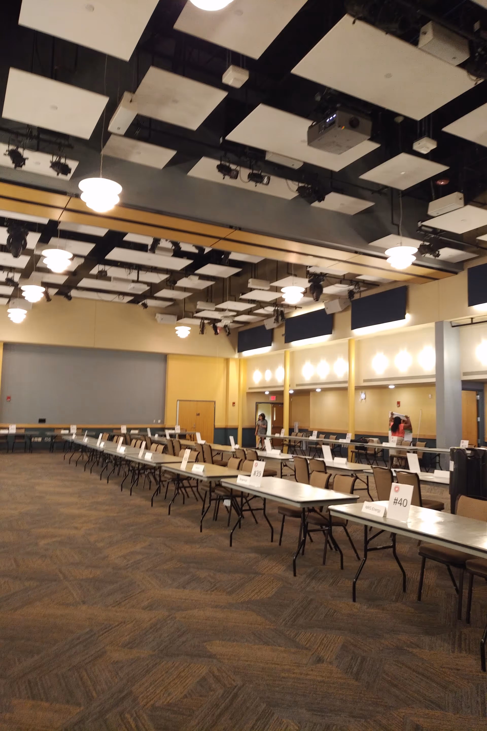 Large dining hall with rows of tables, chairs, and numbered place cards.