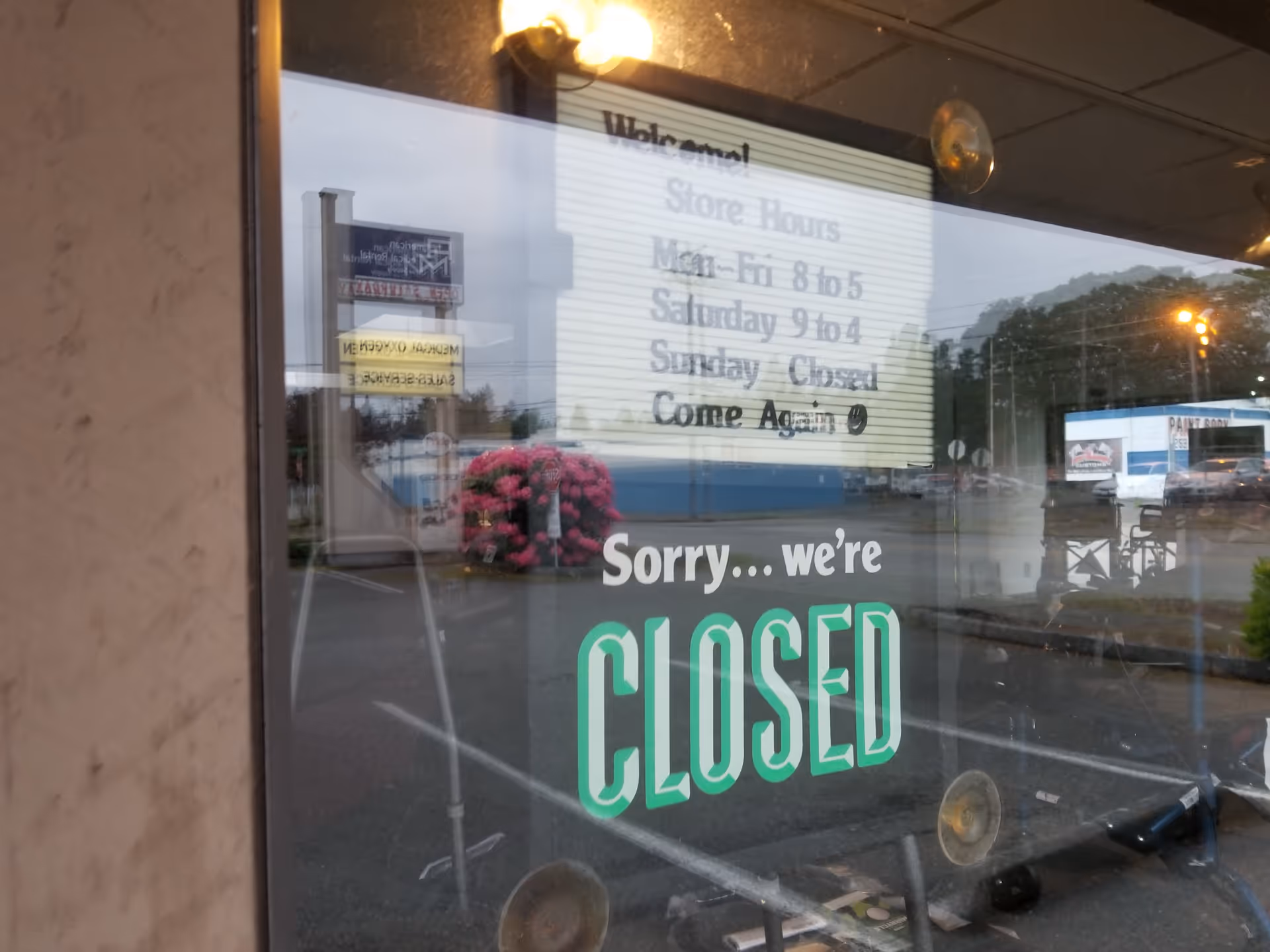 Storefront window shows a large CLOSED sign with reflected hours.