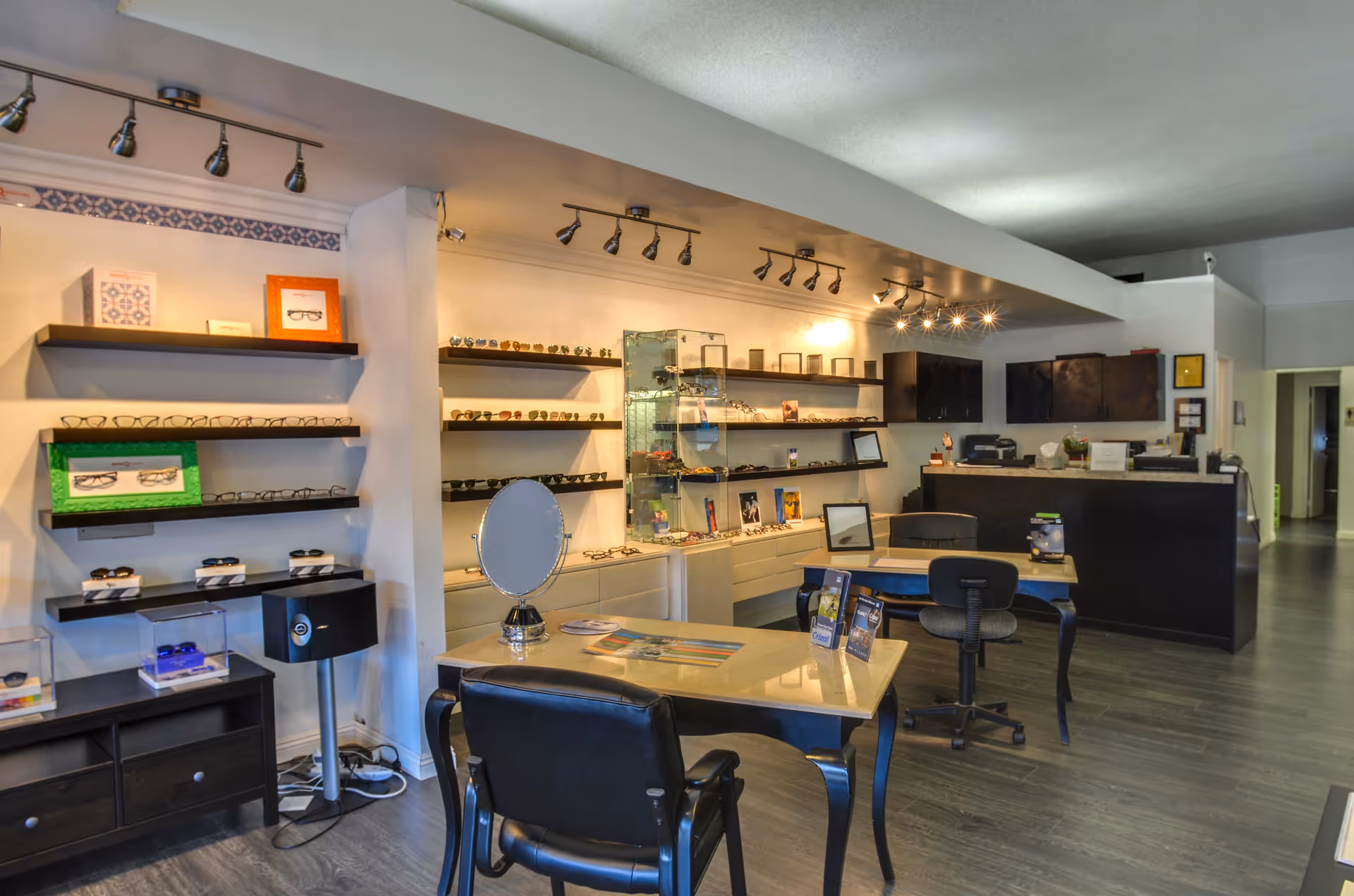 Interior of an optometry clinic with glass shelves, glasses displays, and a reception desk.