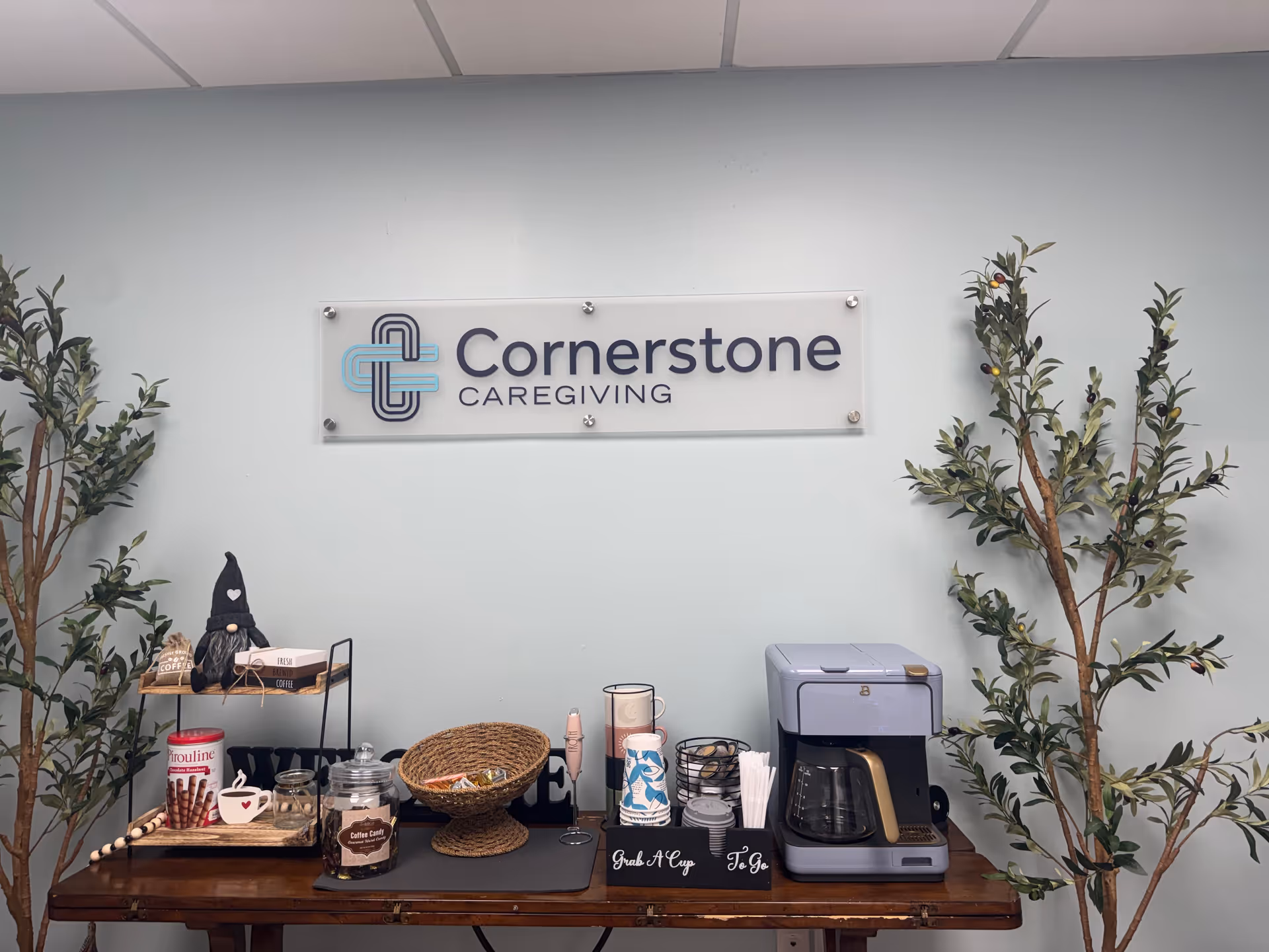 Cornerstone Caregiving sign mounted on a wall above a coffee station inside.