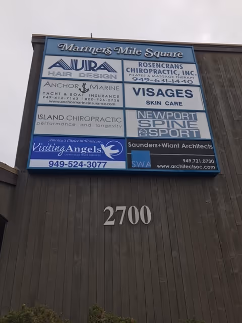 Large building facade with a multi-tenant signboard listing Visiting Angels and others.