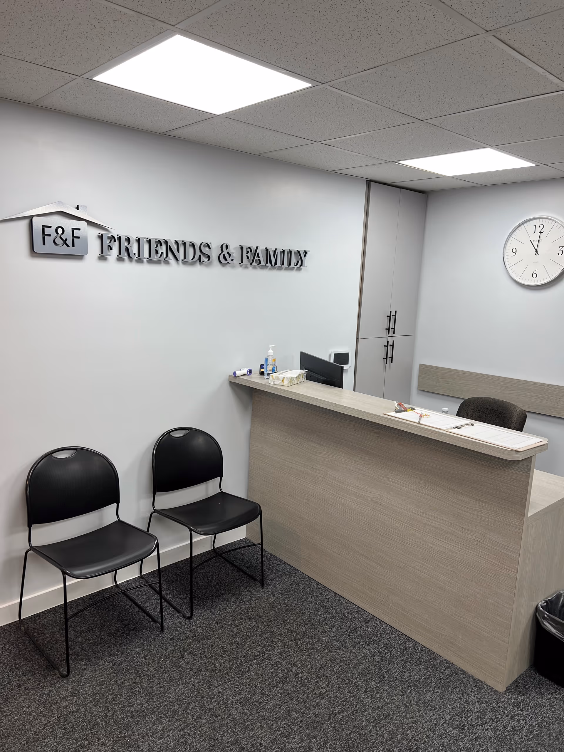 Reception area with desk, two black chairs, clock, and Friends & Family sign