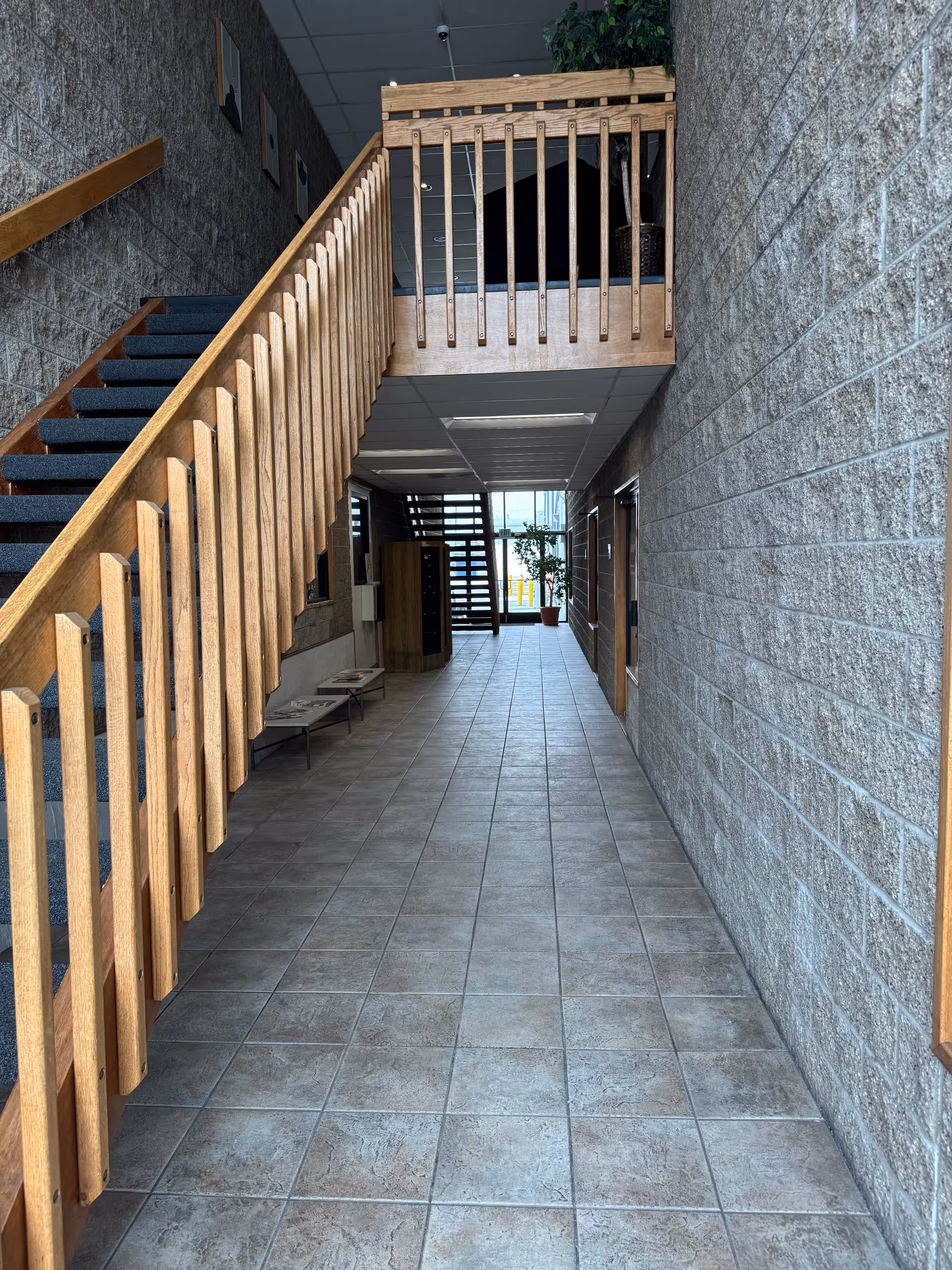 Wide interior hallway with a wooden staircase on the left and a tiled floor.
