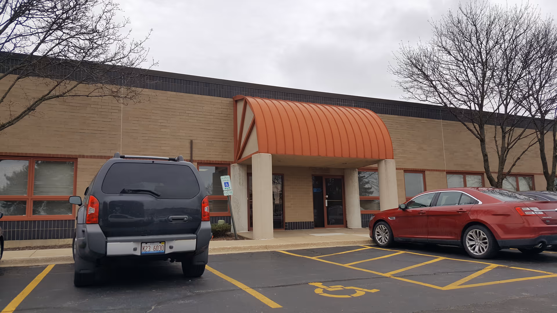 Exterior view of LINCARE facility with orange curved awning, parking lot, and handicap space.