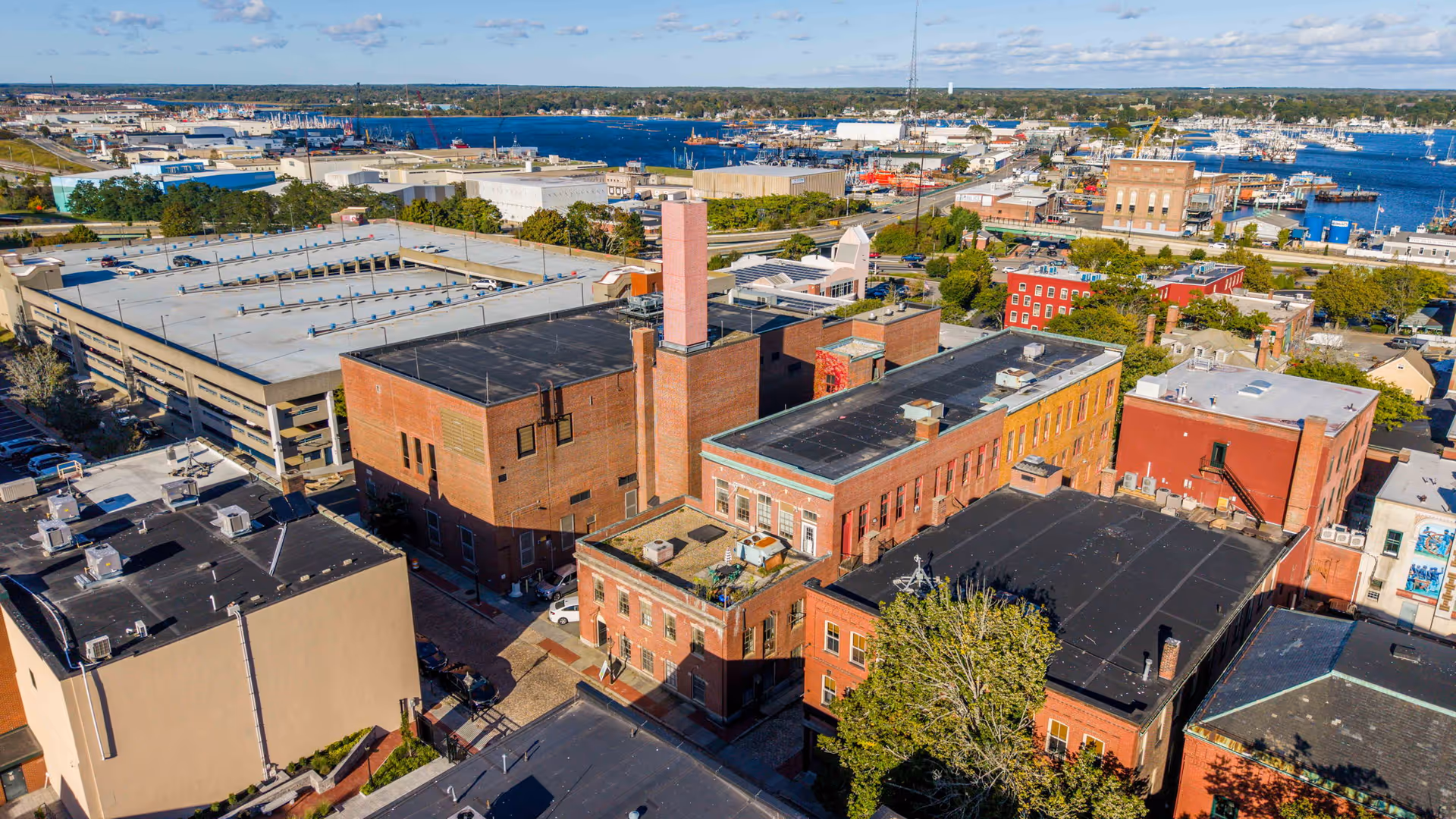 Aerial view of brick campus buildings and city blocks near a harbor.