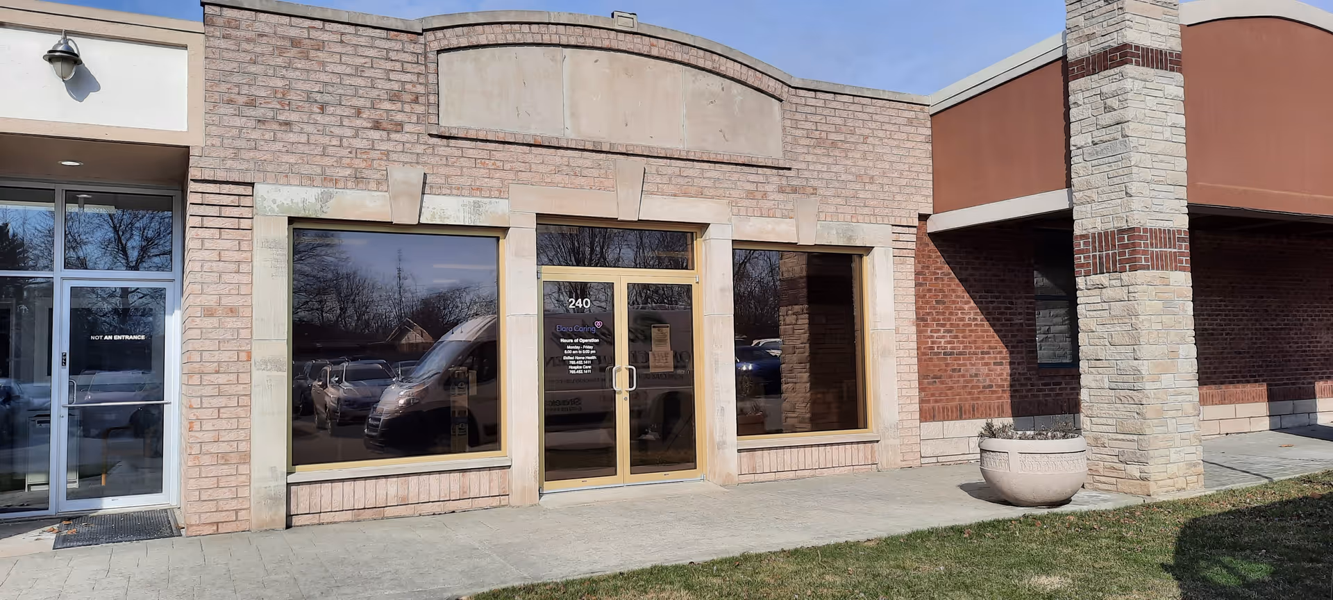 Exterior view of Elara Caring facility entrance with brick facade and glass doors.