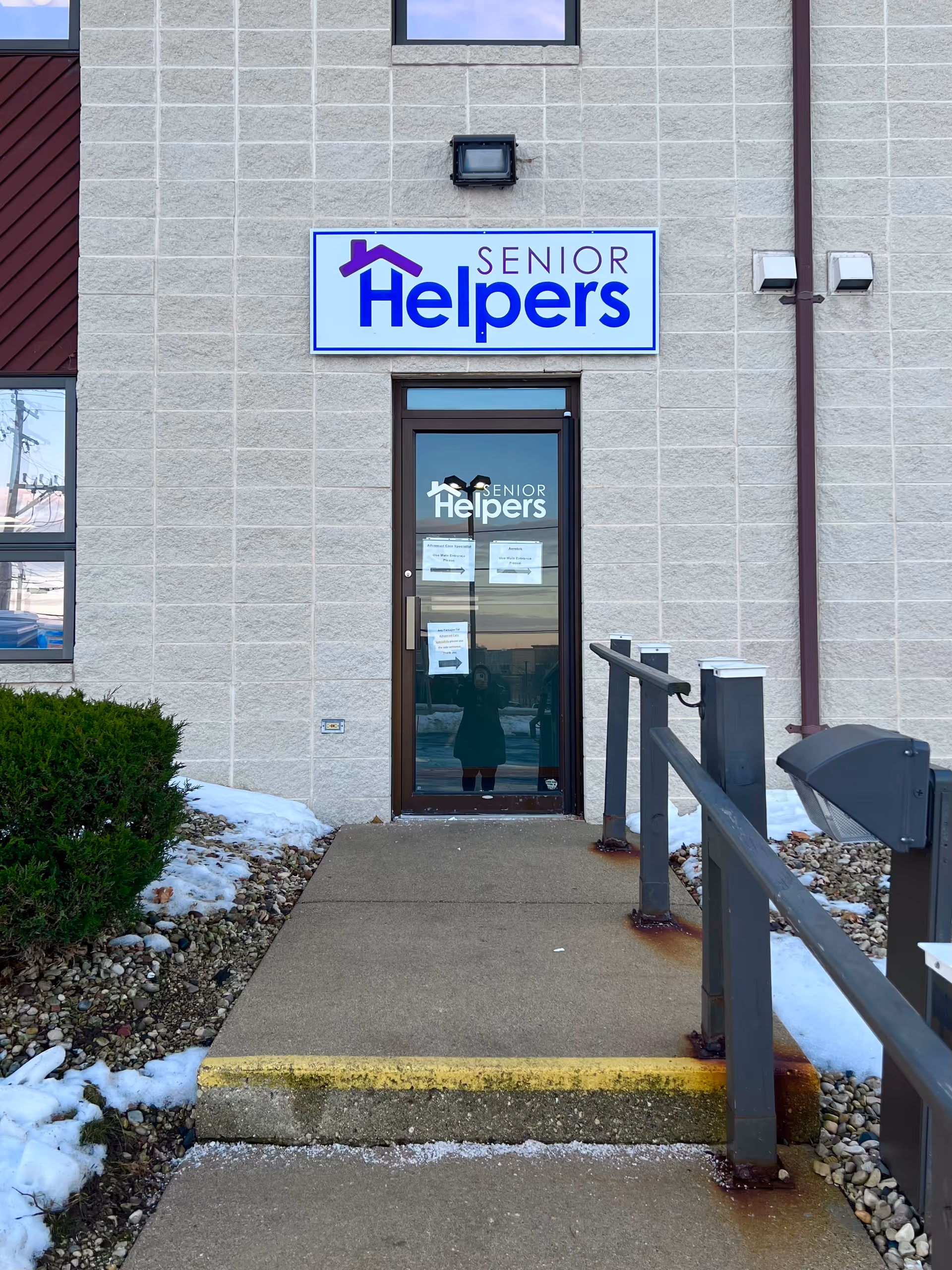 Front exterior of a Senior Helpers facility with entrance door and sign.
