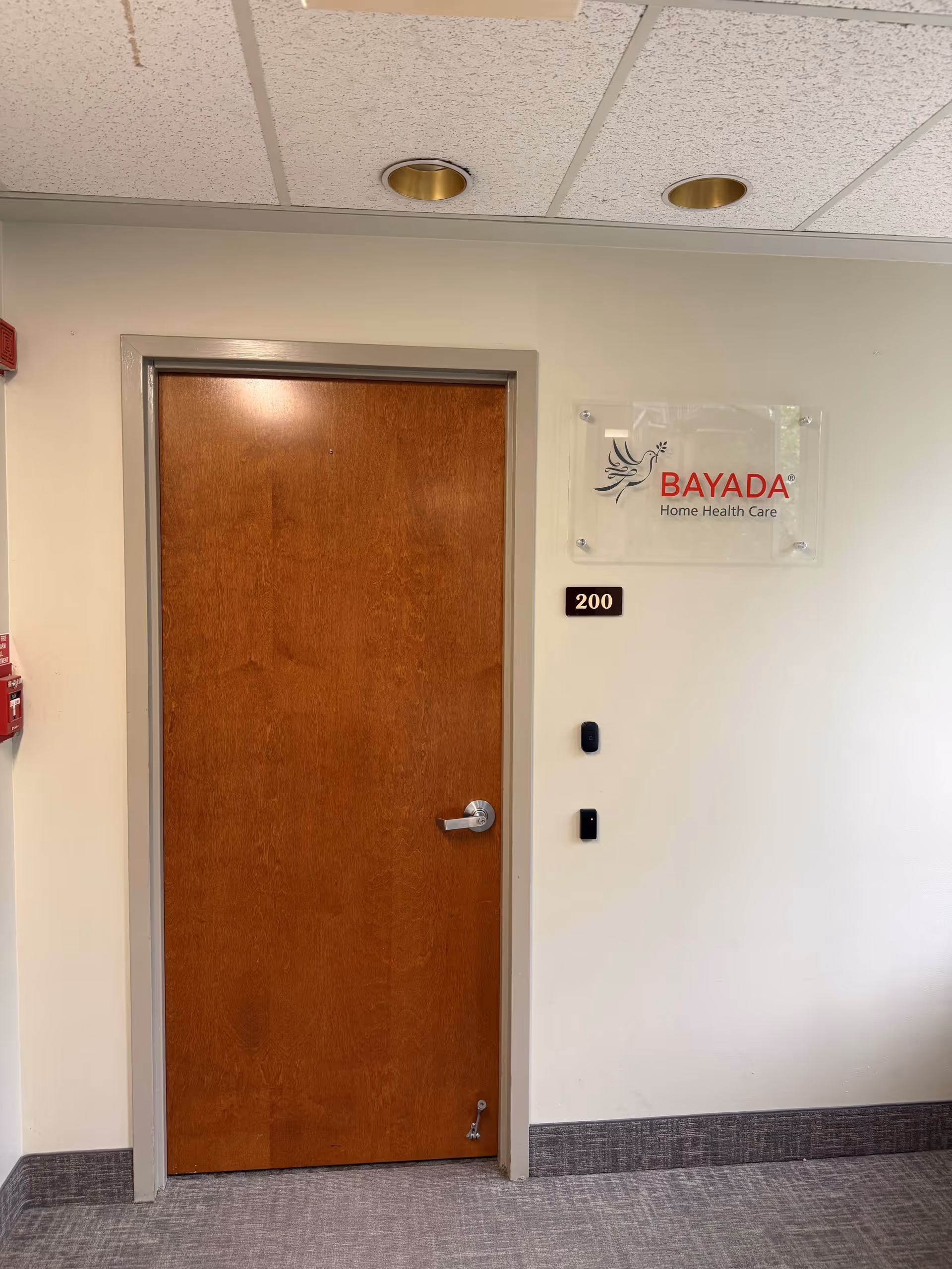 Interior hallway with wooden door marked 200 and BAYADA sign on wall.
