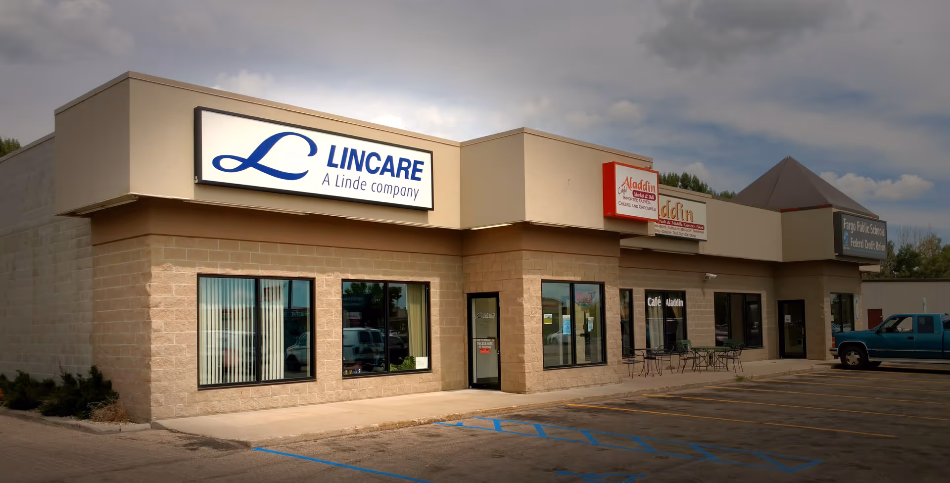 Exterior view of a strip mall with a LINCARE sign, storefront windows, and parking.