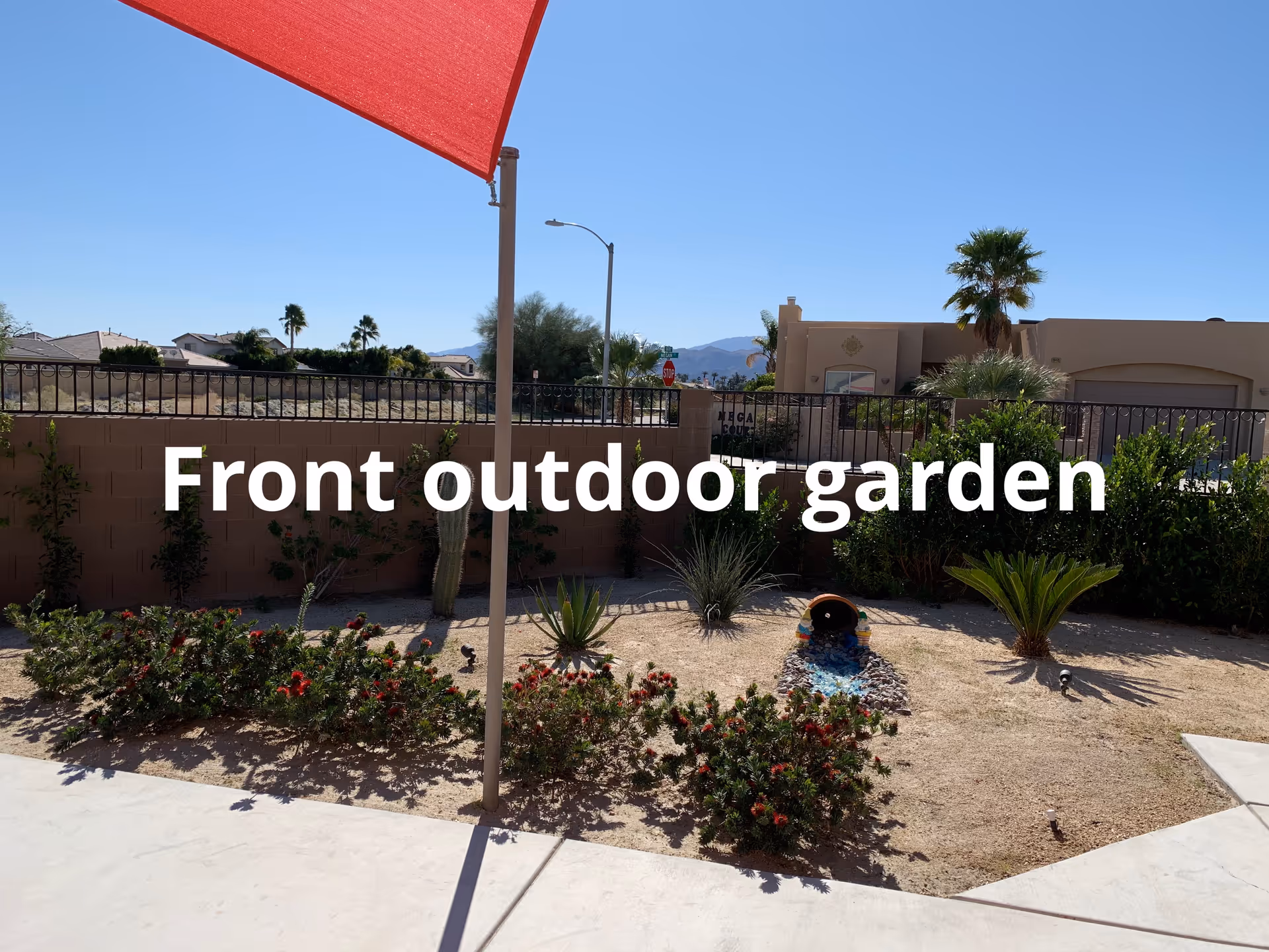 Red shade sail over a desert garden in front of a retirement home.