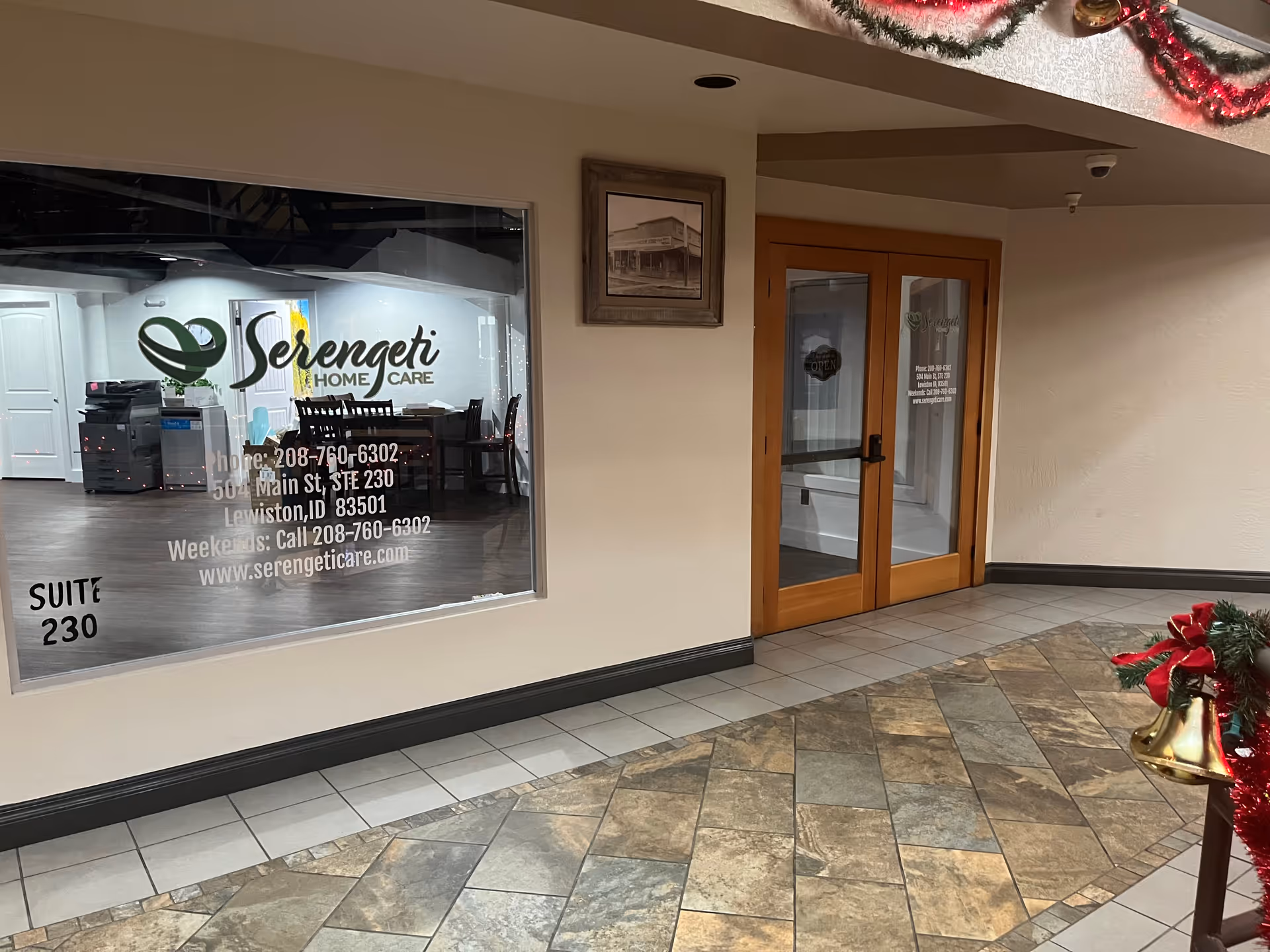 Indoor hallway with a large window display reading Serengeti Home Care and wooden double doors.