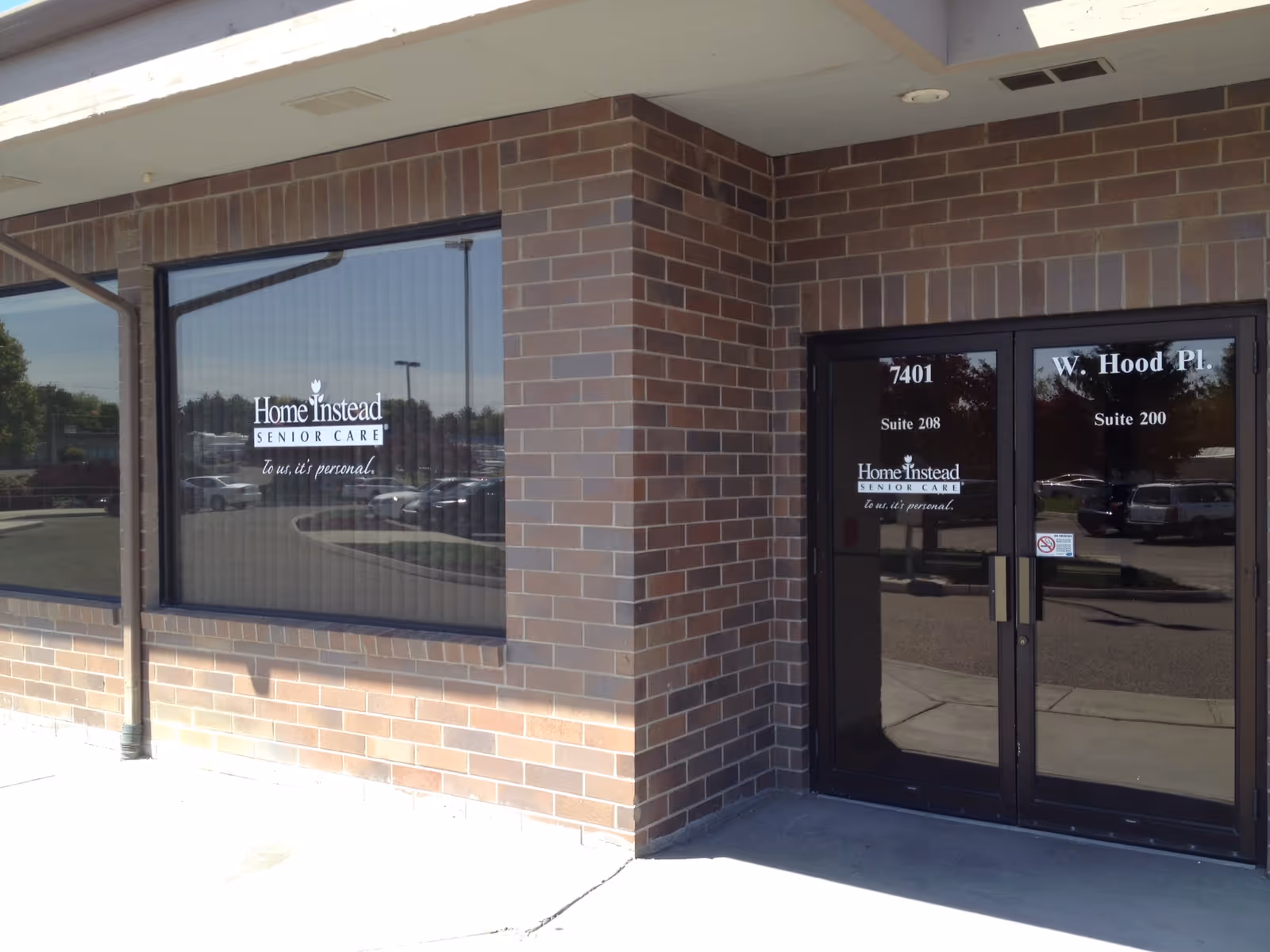 Exterior brick building entrance with Home Instead signage on windows and doors.