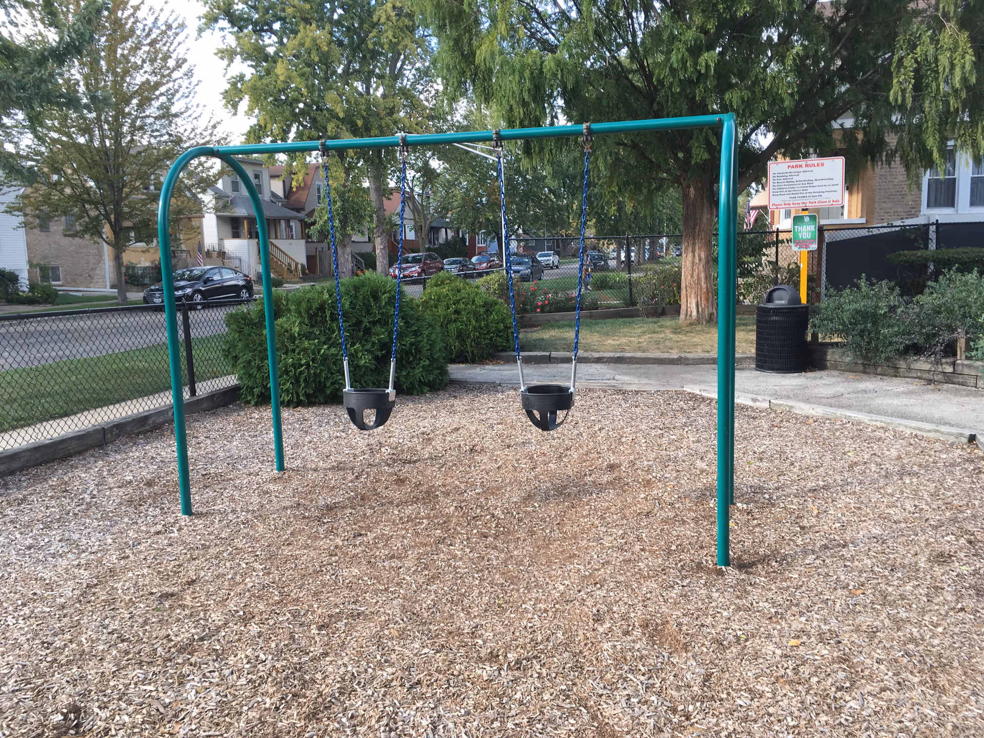 Outdoor playground swings on mulch in a facility courtyard.