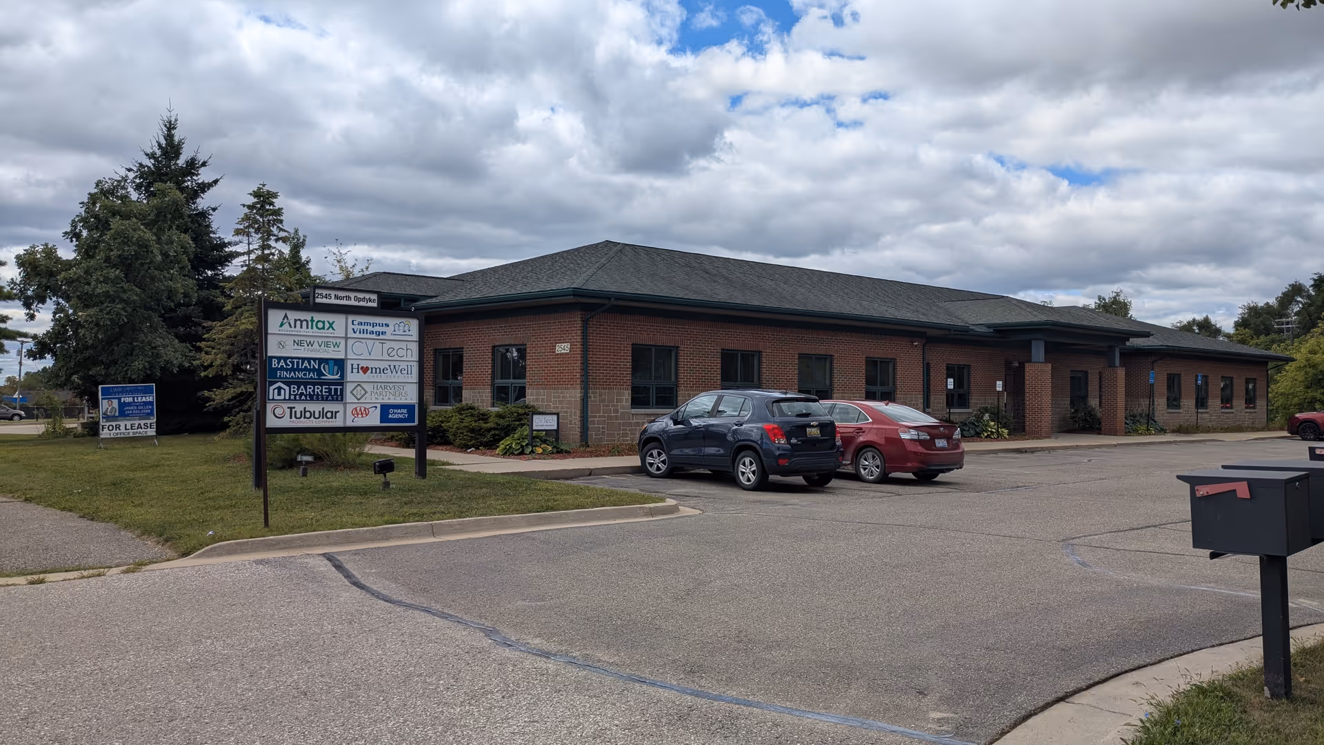 Brick, single-story building with a parking lot and a multi-tenant sign.