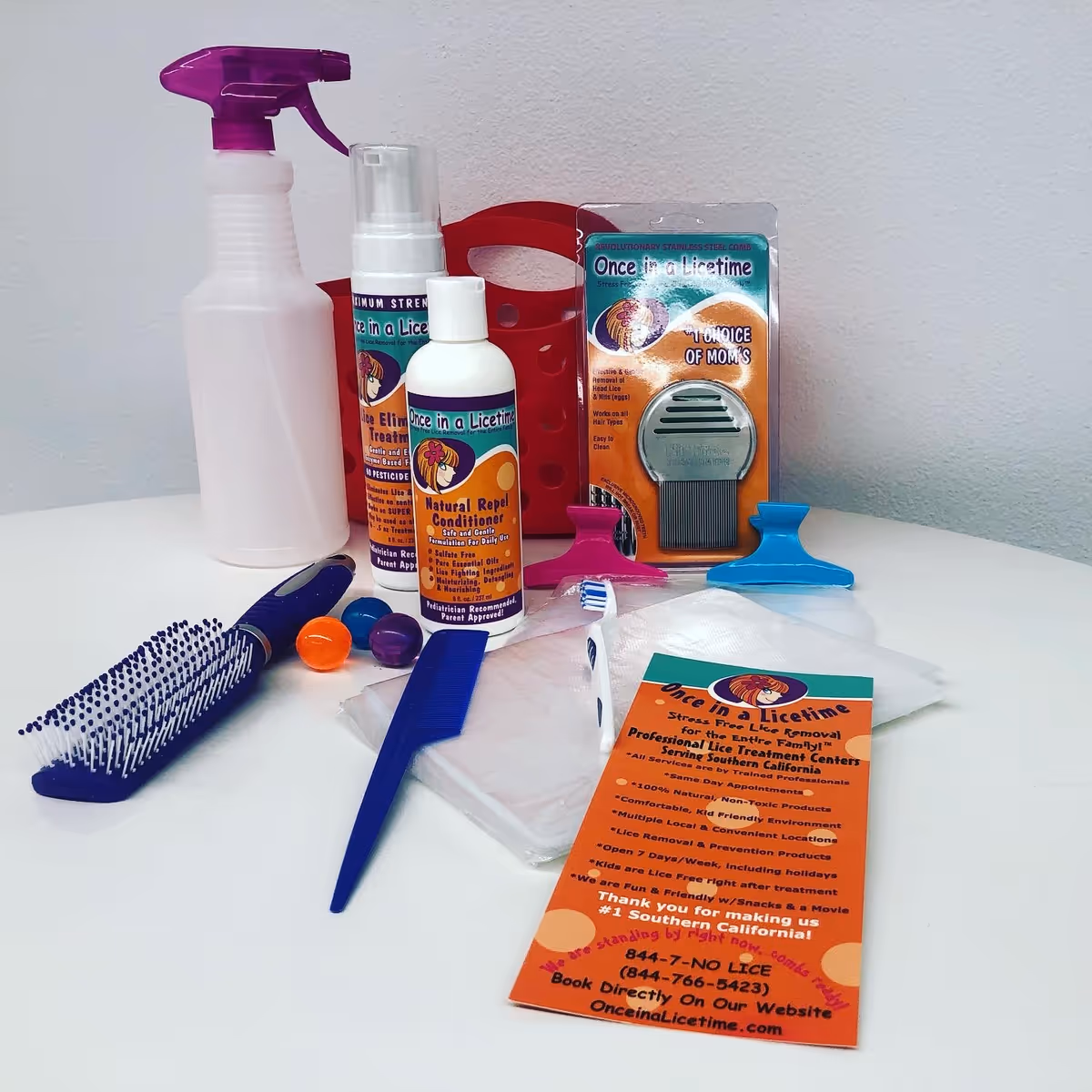 Assorted lice-removal products and tools are arranged on a white tabletop.