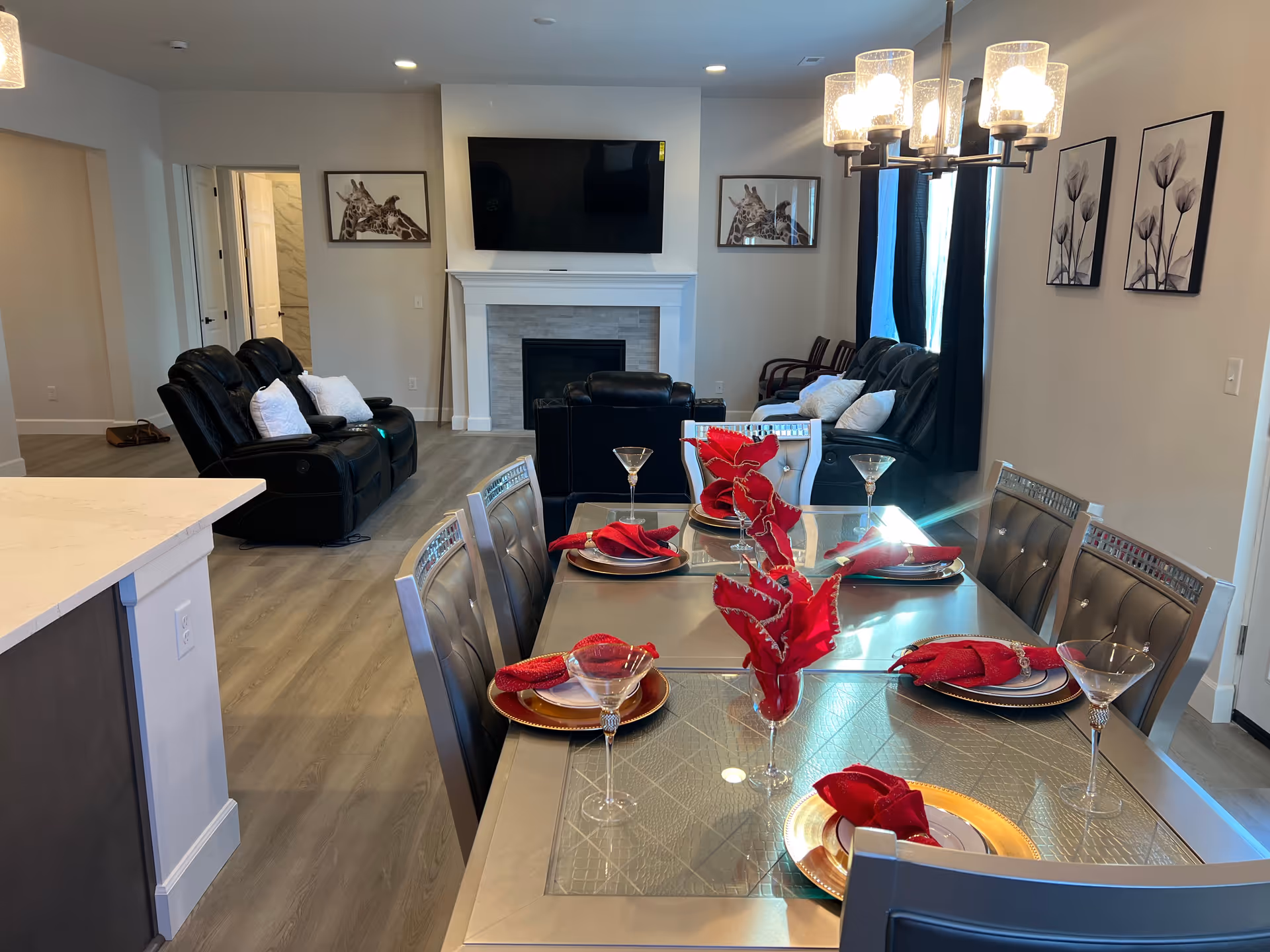Open-concept dining area with a glass table set for a meal and a living room beyond.