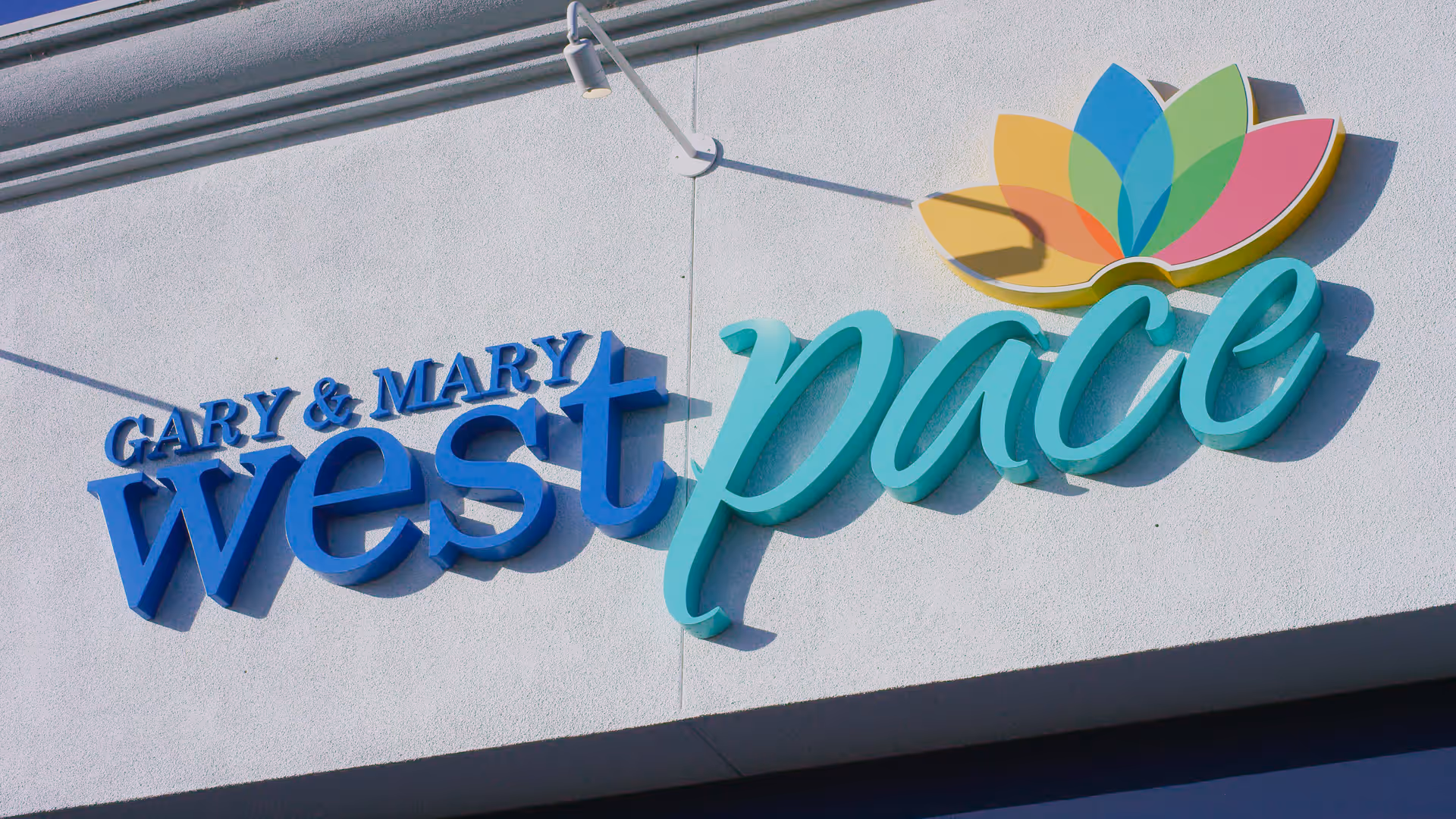 Exterior wall signage reading Gary & Mary West PACE with colorful leaf logo.