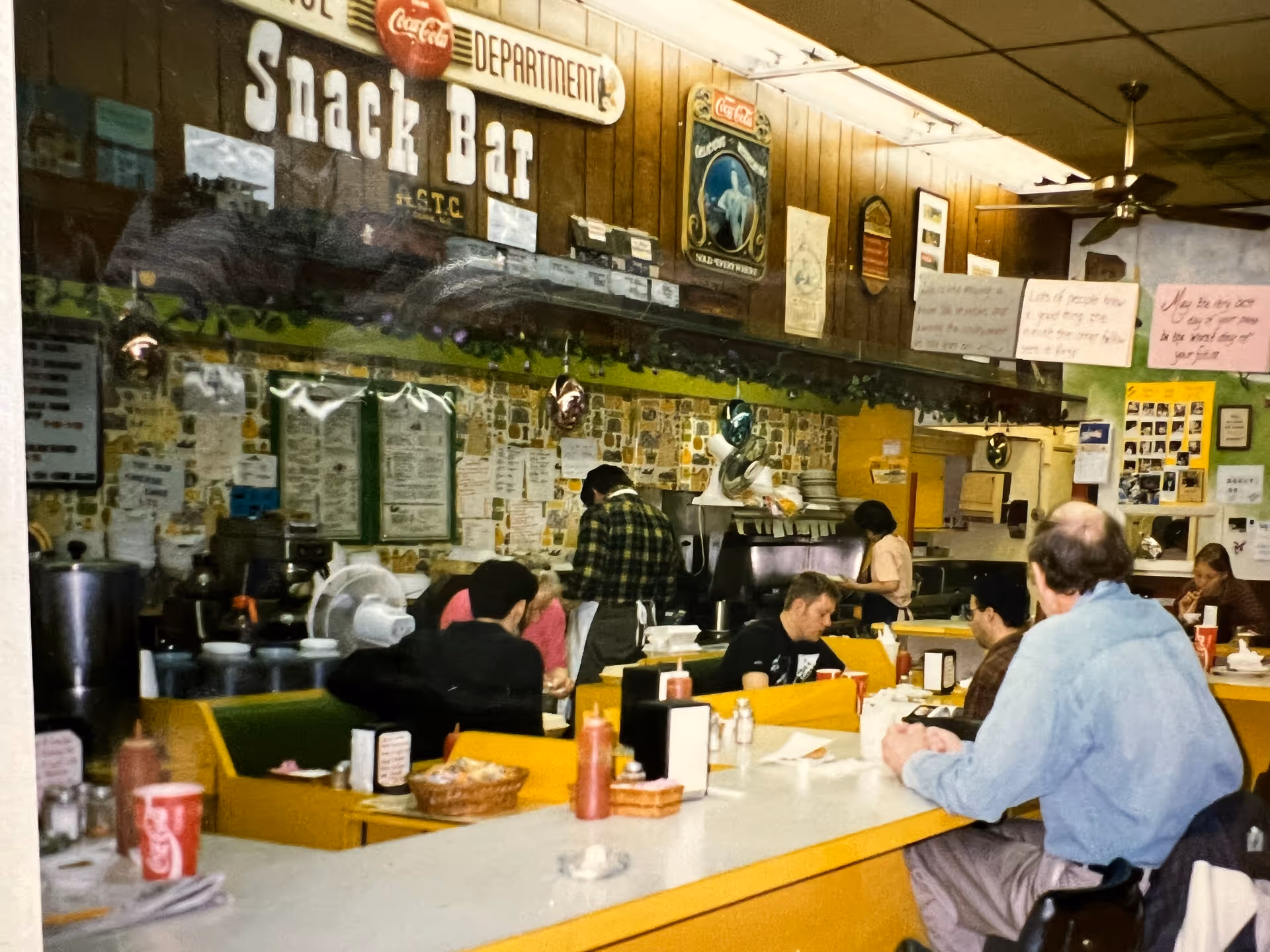 Cafeteria-style snack bar with residents dining at a long counter.
