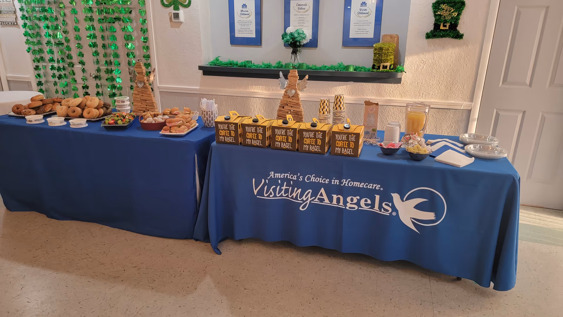 Blue-draped buffet tables display pastries and coffee inside a hallway at Visiting Angels.